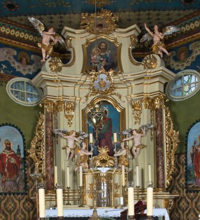 Zdjęcie nr 1: Nastawa ołtarzowa jest architektoniczna, jednoosiowa, jednokondygnacyjna ze zwieńczeniem, ustawiona na wysokim cokole. Ołtarz jest murowany, prostopadłościenny z marmurową mensą z portatylem. Trzy boki ołtarza ujmują malowane na płótnie obrazy w profilowanych, polichromowanych ramach. W polu antepedium znajduje się wyobrażenie architektonicznej nastawy z przedstawieniem baranka na ołtarzu, którą flankują sylwetki św. Piotra i św. Pawła.Tabernakulum ołtarza w formie metalowej skrzynki o wypukłym froncie i drewnianej obudowie w postaci wklęsłych boków zamkniętych parą pilastrów, których trzony przechodzą w spływy wolutowe. Podpory dźwigają profilowany gzyms przebiegający przez całą szerokość tabernakulum, nad frontem dekorowany lambrekinem. Metalowe drzwiczki mają kształt stojącego prostokąta zamkniętego łukiem półkolistym z aplikacjami w postaci kielicha z hostią w glorii, kłosami zbóż i winnego grona. Ponad drzwiczkami znajduje się kartusz z przedstawieniem pelikana. Na tabernakulum umiejscowiony jest tron wystawienia  w formie rzeźbionego ornamentalnego tła, flankowany przez parę rzeźbionych aniołów trzymających lichtarze. Retabulum ujęte jest parą opilastrowanych filarów i parą stojących przed nimi kolumn o kapitelach kompozytowych ustawionych pod kątem względem lica ołtarza. Podpory dźwigają wyłamujące się ponad nimi belkowanie z przerwanymi nad polem środkowym architrawem i fryzem. Zwieńczenie flankuje para spływów wolutowych, zamyka fragment wyłamanego na końcach gzymsu. Retabulum ujmuje para ażurowych, rocaille'owych uszaków, a w zwieńczeniu para figur adorujących aniołów. Trzony pilastrów zdobią rocaille'owe zwisy. W polu środkowym retabulum jest wnęka w formie stojącego prostokąta zamkniętego uskokowym, nadwieszonym łukiem półkolistym, ujęta profilowaną ramą. Wewnątrz znajduje się obraz Matki Boskiej z Dzieciątkiem. Powyżej, pośrodku belkowania umieszczono rocaille'owy kartusz z płaskorzeźbioną, zamkniętą koroną w polu. W zwieńczeniu jest obraz św. Józefa w profilowanej ramie w kształcie zbliżonym do stojącego prostokąta zamkniętego łukiem segmentowym z uskokiem oraz wklęsłymi dolnymi narożami. Szczyt ma formę rokokowego kartusza z malowanym okiem Opatrzności. Na zdobionych motywami rocaille'owymi wolutach spływów znajduje się para aniołów. 

Struktura ołtarza jest polichromowana w kolorze beżowym, trzony kolumn marmoryzowane, ornamentyka i profile złocone. 

