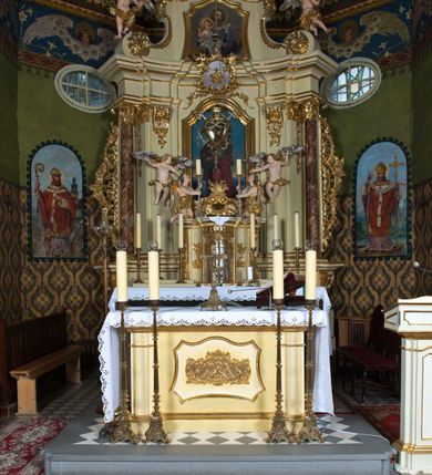 Zdjęcie nr 2: Nastawa ołtarzowa jest architektoniczna, jednoosiowa, jednokondygnacyjna ze zwieńczeniem, ustawiona na wysokim cokole. Ołtarz jest murowany, prostopadłościenny z marmurową mensą z portatylem. Trzy boki ołtarza ujmują malowane na płótnie obrazy w profilowanych, polichromowanych ramach. W polu antepedium znajduje się wyobrażenie architektonicznej nastawy z przedstawieniem baranka na ołtarzu, którą flankują sylwetki św. Piotra i św. Pawła.Tabernakulum ołtarza w formie metalowej skrzynki o wypukłym froncie i drewnianej obudowie w postaci wklęsłych boków zamkniętych parą pilastrów, których trzony przechodzą w spływy wolutowe. Podpory dźwigają profilowany gzyms przebiegający przez całą szerokość tabernakulum, nad frontem dekorowany lambrekinem. Metalowe drzwiczki mają kształt stojącego prostokąta zamkniętego łukiem półkolistym z aplikacjami w postaci kielicha z hostią w glorii, kłosami zbóż i winnego grona. Ponad drzwiczkami znajduje się kartusz z przedstawieniem pelikana. Na tabernakulum umiejscowiony jest tron wystawienia  w formie rzeźbionego ornamentalnego tła, flankowany przez parę rzeźbionych aniołów trzymających lichtarze. Retabulum ujęte jest parą opilastrowanych filarów i parą stojących przed nimi kolumn o kapitelach kompozytowych ustawionych pod kątem względem lica ołtarza. Podpory dźwigają wyłamujące się ponad nimi belkowanie z przerwanymi nad polem środkowym architrawem i fryzem. Zwieńczenie flankuje para spływów wolutowych, zamyka fragment wyłamanego na końcach gzymsu. Retabulum ujmuje para ażurowych, rocaille'owych uszaków, a w zwieńczeniu para figur adorujących aniołów. Trzony pilastrów zdobią rocaille'owe zwisy. W polu środkowym retabulum jest wnęka w formie stojącego prostokąta zamkniętego uskokowym, nadwieszonym łukiem półkolistym, ujęta profilowaną ramą. Wewnątrz znajduje się obraz Matki Boskiej z Dzieciątkiem. Powyżej, pośrodku belkowania umieszczono rocaille'owy kartusz z płaskorzeźbioną, zamkniętą koroną w polu. W zwieńczeniu jest obraz św. Józefa w profilowanej ramie w kształcie zbliżonym do stojącego prostokąta zamkniętego łukiem segmentowym z uskokiem oraz wklęsłymi dolnymi narożami. Szczyt ma formę rokokowego kartusza z malowanym okiem Opatrzności. Na zdobionych motywami rocaille'owymi wolutach spływów znajduje się para aniołów. 

Struktura ołtarza jest polichromowana w kolorze beżowym, trzony kolumn marmoryzowane, ornamentyka i profile złocone. 
