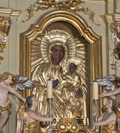 Zdjęcie nr 5: Nastawa ołtarzowa jest architektoniczna, jednoosiowa, jednokondygnacyjna ze zwieńczeniem, ustawiona na wysokim cokole. Ołtarz jest murowany, prostopadłościenny z marmurową mensą z portatylem. Trzy boki ołtarza ujmują malowane na płótnie obrazy w profilowanych, polichromowanych ramach. W polu antepedium znajduje się wyobrażenie architektonicznej nastawy z przedstawieniem baranka na ołtarzu, którą flankują sylwetki św. Piotra i św. Pawła.Tabernakulum ołtarza w formie metalowej skrzynki o wypukłym froncie i drewnianej obudowie w postaci wklęsłych boków zamkniętych parą pilastrów, których trzony przechodzą w spływy wolutowe. Podpory dźwigają profilowany gzyms przebiegający przez całą szerokość tabernakulum, nad frontem dekorowany lambrekinem. Metalowe drzwiczki mają kształt stojącego prostokąta zamkniętego łukiem półkolistym z aplikacjami w postaci kielicha z hostią w glorii, kłosami zbóż i winnego grona. Ponad drzwiczkami znajduje się kartusz z przedstawieniem pelikana. Na tabernakulum umiejscowiony jest tron wystawienia  w formie rzeźbionego ornamentalnego tła, flankowany przez parę rzeźbionych aniołów trzymających lichtarze. Retabulum ujęte jest parą opilastrowanych filarów i parą stojących przed nimi kolumn o kapitelach kompozytowych ustawionych pod kątem względem lica ołtarza. Podpory dźwigają wyłamujące się ponad nimi belkowanie z przerwanymi nad polem środkowym architrawem i fryzem. Zwieńczenie flankuje para spływów wolutowych, zamyka fragment wyłamanego na końcach gzymsu. Retabulum ujmuje para ażurowych, rocaille&#039;owych uszaków, a w zwieńczeniu para figur adorujących aniołów. Trzony pilastrów zdobią rocaille&#039;owe zwisy. W polu środkowym retabulum jest wnęka w formie stojącego prostokąta zamkniętego uskokowym, nadwieszonym łukiem półkolistym, ujęta profilowaną ramą. Wewnątrz znajduje się obraz Matki Boskiej z Dzieciątkiem. Powyżej, pośrodku belkowania umieszczono rocaille&#039;owy kartusz z płaskorzeźbioną, zamkniętą koroną w polu. W zwieńczeniu jest obraz św. Józefa w profilowanej ramie w kształcie zbliżonym do stojącego prostokąta zamkniętego łukiem segmentowym z uskokiem oraz wklęsłymi dolnymi narożami. Szczyt ma formę rokokowego kartusza z malowanym okiem Opatrzności. Na zdobionych motywami rocaille&#039;owymi wolutach spływów znajduje się para aniołów. 

Struktura ołtarza jest polichromowana w kolorze beżowym, trzony kolumn marmoryzowane, ornamentyka i profile złocone. 
