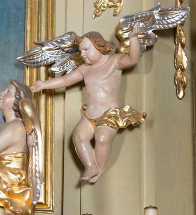 Zdjęcie nr 14: Nastawa ołtarzowa jest architektoniczna, jednoosiowa, jednokondygnacyjna ze zwieńczeniem, ustawiona na wysokim cokole. Ołtarz jest murowany, prostopadłościenny z marmurową mensą z portatylem. Trzy boki ołtarza ujmują malowane na płótnie obrazy w profilowanych, polichromowanych ramach. W polu antepedium znajduje się wyobrażenie architektonicznej nastawy z przedstawieniem baranka na ołtarzu, którą flankują sylwetki św. Piotra i św. Pawła.Tabernakulum ołtarza w formie metalowej skrzynki o wypukłym froncie i drewnianej obudowie w postaci wklęsłych boków zamkniętych parą pilastrów, których trzony przechodzą w spływy wolutowe. Podpory dźwigają profilowany gzyms przebiegający przez całą szerokość tabernakulum, nad frontem dekorowany lambrekinem. Metalowe drzwiczki mają kształt stojącego prostokąta zamkniętego łukiem półkolistym z aplikacjami w postaci kielicha z hostią w glorii, kłosami zbóż i winnego grona. Ponad drzwiczkami znajduje się kartusz z przedstawieniem pelikana. Na tabernakulum umiejscowiony jest tron wystawienia  w formie rzeźbionego ornamentalnego tła, flankowany przez parę rzeźbionych aniołów trzymających lichtarze. Retabulum ujęte jest parą opilastrowanych filarów i parą stojących przed nimi kolumn o kapitelach kompozytowych ustawionych pod kątem względem lica ołtarza. Podpory dźwigają wyłamujące się ponad nimi belkowanie z przerwanymi nad polem środkowym architrawem i fryzem. Zwieńczenie flankuje para spływów wolutowych, zamyka fragment wyłamanego na końcach gzymsu. Retabulum ujmuje para ażurowych, rocaille&#039;owych uszaków, a w zwieńczeniu para figur adorujących aniołów. Trzony pilastrów zdobią rocaille&#039;owe zwisy. W polu środkowym retabulum jest wnęka w formie stojącego prostokąta zamkniętego uskokowym, nadwieszonym łukiem półkolistym, ujęta profilowaną ramą. Wewnątrz znajduje się obraz Matki Boskiej z Dzieciątkiem. Powyżej, pośrodku belkowania umieszczono rocaille&#039;owy kartusz z płaskorzeźbioną, zamkniętą koroną w polu. W zwieńczeniu jest obraz św. Józefa w profilowanej ramie w kształcie zbliżonym do stojącego prostokąta zamkniętego łukiem segmentowym z uskokiem oraz wklęsłymi dolnymi narożami. Szczyt ma formę rokokowego kartusza z malowanym okiem Opatrzności. Na zdobionych motywami rocaille&#039;owymi wolutach spływów znajduje się para aniołów. 

Struktura ołtarza jest polichromowana w kolorze beżowym, trzony kolumn marmoryzowane, ornamentyka i profile złocone. 
