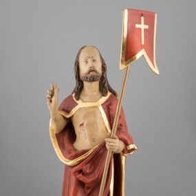 Zdjęcie nr 1: Rzeźba pełna, ustawiona na podstawie na planie nieregularnego koła przedstawia całopostaciowy wizerunek Chrystusa Zmartwychwstałego stojącego frontalnie, w kontrapoście, w lewej ręce trzymającego chorągiew paschalną, z prawą uniesioną w geście błogosławieństwa. Twarz jest szczupła, pociągła, o wysokim czole, delikatnie rzeźbionych rysach i wystających kościach policzkowych, niewielkich oczach zwróconych ku górze, prostym nosie i rozchylonych ustach, okolona krótką brodą skręconą w dwa pukle oraz falowanymi włosami opadającymi na ramiona. Jezus ubrany jest w czerwony płaszcz ze złotą lamówką, odsłaniający tors, zapięty na piersi, opadający na ramiona i plecy, zarzucony z przodu na lewe przedramię, przesłaniając partie nóg. Ciało jest szczupłe, o delikatnym modelunku z zaznaczonymi śladami męki. Polichromia naturalistyczna.