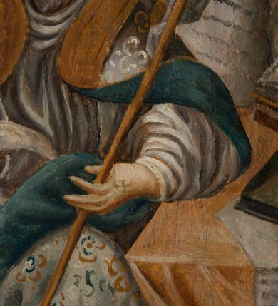 Zdjęcie nr 4: Obraz uzyskał kształt stojącego prostokąta, ujętego prostą, malowaną na jasnobrązowo ramę. Przedstawienie św. Ambrożego w pracowni zostało wkomponowane w pole w kształcie stojącego prostokąta ujętego u dołu i u góry przeciwstawną parą odcinkowych łuków nadwieszonych. Wokół pola obrazowego widoczne jest w odcieniach ciemnego drewna mazerowanie. Centrum kompozycji stanowi sylwetka siedzącego świętego w pracowni przy nakrytym żółtą tkaniną stole o wolutowych, rzeźbionych nogach. Ambroży zwrócony jest w trzech czwartych w prawo z nogami nieznacznie odchylonymi w lewo. Jego pociągłą twarz okala siwiejący krótki zarost. W prawej ręce trzyma otwartą księgę w czerwonej oprawie, zaś lewą podtrzymuje złoty pastorał o zdobnej krzywaśni, z której końca zwisa paniselus. Ubrany jest we wzorzystą jasną kapę podbitą niebieską podszewką. Okrywa ona białą albę. Na jego rękach widoczne są rękawiczki pontyfikalne, a na głowie mitra biskupia z tej samej tkaniny co kapa. Na blacie pomiędzy innymi leży na pulpicie otwarta księga. Widoczny jest także kałamarz oraz zwisający z krawędzi blatu zwój pergaminu przyciśnięty księgą. Przed stołem z lewej strony stoi pleciony słomiany ul. W głębi pracowni-komnaty widoczne jest łoże z jasnym namiotowym baldachimem i zielonymi zasłonami. Z prawej strony widać fragment architektonicznego obramienia kominka, a z lewej półokrągłe okno wypełnione gomółkami.