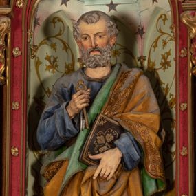 Zdjęcie nr 1: Pełnoplastyczna, polichromowana figura ustawiona na niewysokim, prostopadłościennym postumencie ukazuje św. Piotra Apostoła. Święty został przedstawiony frontalnie w nieznacznym kontrapoście jako starszy, siwiejący mężczyzna z krótką brodą. W lewej dłoni na wysokości pasa podtrzymuje zamkniętą księgę w ozdobnej oprawie, natomiast w prawej ręce zgiętej w łokciu przy piersi ma złoty i srebrny klucz. Święty ma pociągłą twarz o jasnej karnacji, rumiane policzki i wydane zakola na wysokim czole.  Spojrzenie jego ciemnych, zamyślonych oczu skierowane jest przed siebie. Apostoł ubrany jest w długą ciemnoniebieską tunikę odsłaniającą u spodu fragmenty bosych stóp. Przez lewe ramię ma przerzucony obszerny, obficie drapowany, żółty płaszcz z zieloną podszewką ze złotą lamówką. Na cokole widnieje złocona inskrypcja „Św(ięty) Piotr&quot;.