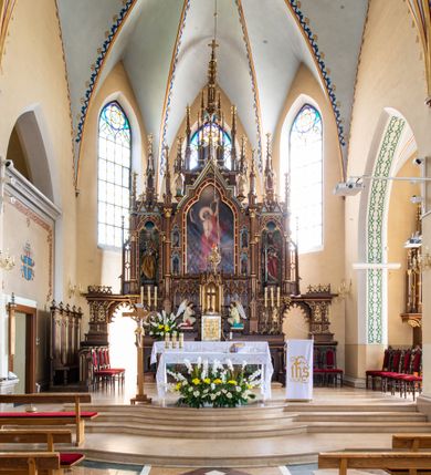 Zdjęcie nr 2: Pełnoplastyczna, polichromowana figura ustawiona na niewysokim, prostopadłościennym postumencie ukazuje św. Piotra Apostoła. Święty został przedstawiony frontalnie w nieznacznym kontrapoście jako starszy, siwiejący mężczyzna z krótką brodą. W lewej dłoni na wysokości pasa podtrzymuje zamkniętą księgę w ozdobnej oprawie, natomiast w prawej ręce zgiętej w łokciu przy piersi ma złoty i srebrny klucz. Święty ma pociągłą twarz o jasnej karnacji, rumiane policzki i wydane zakola na wysokim czole.  Spojrzenie jego ciemnych, zamyślonych oczu skierowane jest przed siebie. Apostoł ubrany jest w długą ciemnoniebieską tunikę odsłaniającą u spodu fragmenty bosych stóp. Przez lewe ramię ma przerzucony obszerny, obficie drapowany, żółty płaszcz z zieloną podszewką ze złotą lamówką. Na cokole widnieje złocona inskrypcja „Św(ięty) Piotr&quot;.