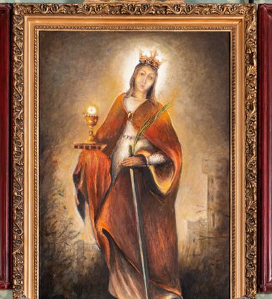 Zdjęcie nr 1: Obraz w kształcie stojącego prostokątna, w profilowanych i złoconych ramach dekorowanych ornamentem roślinnym, w zwieńczeniu para płaskorzeźbionych aniołów adorujących kielich eucharystyczny. W centrum kompozycji znajduje się całopostaciowe, frontalne przedstawienie św. Barbary stojącej w kontrapoście. Święta została przedstawiona jako młoda kobieta ubrana w długą białą suknię oraz obszerny czerwony płaszcz spięty na piersiach ozdobną klamrą, ze złotą koroną na głowie, wokół której jaśnieje aureola. W lewym ręku trzyma miecz i gałązkę palmy, a w prawym kielich z hostią ustawiony na zamkniętej księdze. W głębi, z prawej strony widoczna wieża. Tło obrazu jest jednolite, beżowo-brązowe, kolorystyka ciemna, zgaszona.