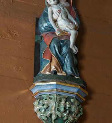 Zdjęcie nr 4: Pieta w Jawiszowicach reprezentuje Pietę w tzw. typie Pieta corpusculum. Przedstawiono tutaj pełnopostaciową figurę siedzącej Marii, trzymającą na kolanach martwe ciało Chrystusa. Matka Boska jest lekko pochylona w prawą stronę. Obiema rękami podtrzymuje na swoich kolanach Chrystusa, opartego o jej prawe przedramię. Prawą ręką trzyma go za bok, a lewą kładzie na jego udach. Ma owalną twarz o jasnej karnacji z wysokim czołem. Jej oczy są duże, wyraźne. Maria ma długi, prosty nos, czerwone usta, rumiane policzki i nieznacznie zaznaczone zmarszczki podkreślające jej cierpienie. Matka Boska odziana jest w złotą tunikę i ciemnobłękitny maforion z czerwonym podbiciem lamowany złotem, okrywający jej postać. Fałdy płaszcza są misowate, miękko rzeźbione. Spód szaty odsłania brunatne ciżmy. Martwy Chrystus jest wielkości dziecka. Jego ciało z odchyloną głową ułożone jest prawie schodkowo. Twarz z zamkniętymi oczami okala zarost oraz włosy. Na głowie ma koronę cierniową, spod której sączą się na czoło stróżki krwi. Krew cieknie także z przebitego boku. Biodra Chrystusa okrywa jasne, miękko drapowane perizonium.  
Rzeźba stoi na współczesnej, stylizowanej na gotycką pięciobocznej konsoli. Jej profilowany cokół podtrzymuje wspornik opleciony  srebrzystymi i złotymi liśćmi akantu. Krawędzie konsoli są pozłocone.