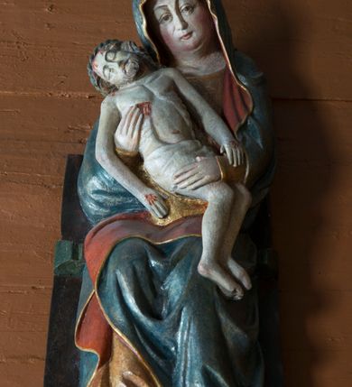 Zdjęcie nr 5: Pieta w Jawiszowicach reprezentuje Pietę w tzw. typie Pieta corpusculum. Przedstawiono tutaj pełnopostaciową figurę siedzącej Marii, trzymającą na kolanach martwe ciało Chrystusa. Matka Boska jest lekko pochylona w prawą stronę. Obiema rękami podtrzymuje na swoich kolanach Chrystusa, opartego o jej prawe przedramię. Prawą ręką trzyma go za bok, a lewą kładzie na jego udach. Ma owalną twarz o jasnej karnacji z wysokim czołem. Jej oczy są duże, wyraźne. Maria ma długi, prosty nos, czerwone usta, rumiane policzki i nieznacznie zaznaczone zmarszczki podkreślające jej cierpienie. Matka Boska odziana jest w złotą tunikę i ciemnobłękitny maforion z czerwonym podbiciem lamowany złotem, okrywający jej postać. Fałdy płaszcza są misowate, miękko rzeźbione. Spód szaty odsłania brunatne ciżmy. Martwy Chrystus jest wielkości dziecka. Jego ciało z odchyloną głową ułożone jest prawie schodkowo. Twarz z zamkniętymi oczami okala zarost oraz włosy. Na głowie ma koronę cierniową, spod której sączą się na czoło stróżki krwi. Krew cieknie także z przebitego boku. Biodra Chrystusa okrywa jasne, miękko drapowane perizonium.  
Rzeźba stoi na współczesnej, stylizowanej na gotycką pięciobocznej konsoli. Jej profilowany cokół podtrzymuje wspornik opleciony  srebrzystymi i złotymi liśćmi akantu. Krawędzie konsoli są pozłocone.