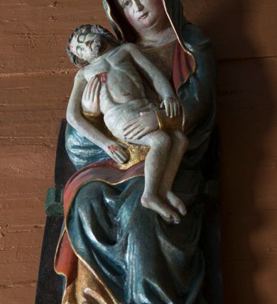 Zdjęcie nr 6: Pieta w Jawiszowicach reprezentuje Pietę w tzw. typie Pieta corpusculum. Przedstawiono tutaj pełnopostaciową figurę siedzącej Marii, trzymającą na kolanach martwe ciało Chrystusa. Matka Boska jest lekko pochylona w prawą stronę. Obiema rękami podtrzymuje na swoich kolanach Chrystusa, opartego o jej prawe przedramię. Prawą ręką trzyma go za bok, a lewą kładzie na jego udach. Ma owalną twarz o jasnej karnacji z wysokim czołem. Jej oczy są duże, wyraźne. Maria ma długi, prosty nos, czerwone usta, rumiane policzki i nieznacznie zaznaczone zmarszczki podkreślające jej cierpienie. Matka Boska odziana jest w złotą tunikę i ciemnobłękitny maforion z czerwonym podbiciem lamowany złotem, okrywający jej postać. Fałdy płaszcza są misowate, miękko rzeźbione. Spód szaty odsłania brunatne ciżmy. Martwy Chrystus jest wielkości dziecka. Jego ciało z odchyloną głową ułożone jest prawie schodkowo. Twarz z zamkniętymi oczami okala zarost oraz włosy. Na głowie ma koronę cierniową, spod której sączą się na czoło stróżki krwi. Krew cieknie także z przebitego boku. Biodra Chrystusa okrywa jasne, miękko drapowane perizonium.  
Rzeźba stoi na współczesnej, stylizowanej na gotycką pięciobocznej konsoli. Jej profilowany cokół podtrzymuje wspornik opleciony  srebrzystymi i złotymi liśćmi akantu. Krawędzie konsoli są pozłocone.