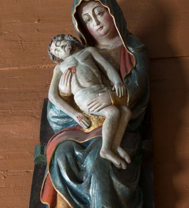 Zdjęcie nr 7: Pieta w Jawiszowicach reprezentuje Pietę w tzw. typie Pieta corpusculum. Przedstawiono tutaj pełnopostaciową figurę siedzącej Marii, trzymającą na kolanach martwe ciało Chrystusa. Matka Boska jest lekko pochylona w prawą stronę. Obiema rękami podtrzymuje na swoich kolanach Chrystusa, opartego o jej prawe przedramię. Prawą ręką trzyma go za bok, a lewą kładzie na jego udach. Ma owalną twarz o jasnej karnacji z wysokim czołem. Jej oczy są duże, wyraźne. Maria ma długi, prosty nos, czerwone usta, rumiane policzki i nieznacznie zaznaczone zmarszczki podkreślające jej cierpienie. Matka Boska odziana jest w złotą tunikę i ciemnobłękitny maforion z czerwonym podbiciem lamowany złotem, okrywający jej postać. Fałdy płaszcza są misowate, miękko rzeźbione. Spód szaty odsłania brunatne ciżmy. Martwy Chrystus jest wielkości dziecka. Jego ciało z odchyloną głową ułożone jest prawie schodkowo. Twarz z zamkniętymi oczami okala zarost oraz włosy. Na głowie ma koronę cierniową, spod której sączą się na czoło stróżki krwi. Krew cieknie także z przebitego boku. Biodra Chrystusa okrywa jasne, miękko drapowane perizonium.  
Rzeźba stoi na współczesnej, stylizowanej na gotycką pięciobocznej konsoli. Jej profilowany cokół podtrzymuje wspornik opleciony  srebrzystymi i złotymi liśćmi akantu. Krawędzie konsoli są pozłocone.