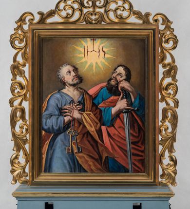 Zdjęcie nr 2: Feretron obrazowy ujęty jest akantową, ażurową, złoconą ramą i osadzony na prostopadłościennej, profilowanej podstawie z parą otworów na służące do noszenia drążki. Pola obrazowe mają kształt stojących prostokątów. Na awersie znajduje się przedstawienie Świętej Rodziny. Siedząca po lewej stronie kompozycji, zwrócona w trzech czwartych w lewo Maria ukazana jest do wysokości kolan. Owalną, pełną twarz charakteryzują wyraziście modelowane rysy. Zebrane na wysokości karku, ciemnobrązowe, rozdzielone przedziałkiem włosy opadają na plecy. Maria ubrana jest w jasnoczerwoną, przewiązaną błękitną szarfą suknię z białym kołnierzem szerokiego dekoltu oraz częściowo osłaniający sylwetkę ciemnoniebieski płaszcz. Z głowy zsuwa się opadająca na ramiona jasnożółta chusta. Prawa ręka opuszczona jest w dół, lewą podtrzymuje stojące na jej kolanach, zwrócone na wprost Dzieciątko. Jego nagą sylwetkę częściowo osłania trzymana przez Marię biała chusta, której poła znajduje się także pod stopami Jezusa. Dzieciątko wyginając nieznacznie sylwetkę, zwraca się ku stojącemu po prawej stronie św. Józefowi. Prawą rękę unosi w geście błogosławieństwa, lewą ujmuje głowę mężczyzny, przytulając ją do swej twarzy. Zwrócony nieznacznie w trzech czwartych w prawo św. Józef ukazany jest do wysokości kolan. Pociągłą twarz charakteryzują wyraziste rysy mężczyzny w podeszłym wieku, z krótkim, siwym zarostem i włosami. Ubrany jest w przewiązaną w pasie niebieską suknię oraz narzucony na ramiona brązowy płaszcz. W lewej dłoni trzyma laskę zwieńczoną pękiem ulistnionych gałązek z drobnymi, białymi kwiatami. Wokół głów Marii i Jezusa znajdują się nimby, nad głową św. Józefa jest aureola. Postaci usytuowane są w pomieszczeniu z dużym oknem, w którym widać fragment błękitnego nieba. Ciemnobrązową ścianę tuż za Marią przesłania podpięta w lewym górnym rogu kompozycji ciemnozielona kotara obszyta dołem złoconą frędzlą. Kolorystyka obrazu utrzymana jest w nasyconych, zróżnicowanych światłocieniowo barwach. Drapowania tkanin charakteryzuje bogactwo fałdowań.
Rewers feretronu stanowi wizerunek św. Piotra i św. Pawła ukazanych półpostaciowo. Na pierwszy plan wysunięta jest nieznacznie postać św. Piotra zwróconego w trzech czwartych w lewo. Odchyloną głowę charakteryzuje owalna twarz o plastycznie modelowanych rysach i krótkim, siwym zaroście. Włosy są krótkie i siwe. Święty ubrany jest w szarobłękitną suknię z kołnierzem oraz narzucony na plecy i przewieszony przez lewą rękę jasnobrązowy płaszcz. Dłonie są skrzyżowane na piersiach, w lewej apostoł trzyma zawieszone na czerwonej tasiemce dwa klucze, złoty i srebrny. Prawą stronę kompozycji zajmuje zwrócona na wprost sylwetka św. Pawła. Zwróconą w trzech czwartych w prawo charakteryzuje pociągła twarz o niezwykle wyrazistych rysach, wydatnym nosie oraz długim, gęstym, ciemnobrązowym zaroście. Święty ubrany jest w niebieską suknię i czerwony, osłaniający sylwetkę płaszcz. Oburącz podtrzymuje rękojeść miecza, dodatkowo wspierając głowę na lewej dłoni. Święci spoglądają w kierunku unoszącej się pośrodku ponad nimi promienistej glorii z monogramem chrystologicznym. Tło jest utrzymane w odcieniach brązu. Kolorystykę obrazu charakteryzują nasycone, zróżnicowane światłocieniowo barwy. Drapowania tkanin charakteryzuje bogactwo fałdowań. 
