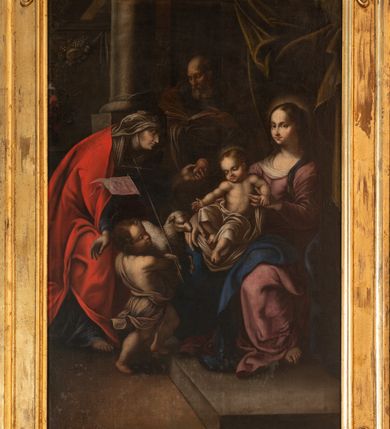 Zdjęcie nr 5: Obraz ukazujący "Rodzinę Marii" uzyskał kształt stojącego prostokąta. Pole obrazowe zamyka drewniana, fazowana rama w narożach zdobiona motywem roślinnym. Z lewej strony na kamiennym postumencie jednostopniowym siedzi na krześle Maria, trzymająca na kolanach Dzieciątko Jezus. Madonna została ukazana w ujęciu en trois quarts w prawo. Jej żywe spojrzenie skierowane jest w stronę widza. Ma owalną twarz o pucułowatych, rumianych policzkach, wysokim czole, wyrazistym nosie i czerwonych ustach. Brązowe włosy z widocznym przedziałkiem na środku głowy zostały zaczesane do tyłu. Madonna ubrana jest w szkarłatnofioletową suknię z dekoltem nieznacznie przysłoniętym białą chustą. Opadająca ku ziemi sztywnymi draperiami suknia odsłania fragment jej lewej stopy. Częściowo na lewym ramieniu oraz na kolanach widać ciemnoniebieski płaszcz. Jej głowę otacza niewielka świetlista poświata. Madonna obiema rękami podtrzymuje małego Jezusa. Dzieciątko na kolanach matki siedzi na białej chuście, która równocześnie okrywa dolną część jego postaci. Chrystus został ujęty en trois quarts w prawo. Jest to korpulentna postać o jasnej karnacji ciała i nogach zgiętych w kolanach. Lewą rączkę wspiera na lewej dłoni Maryi, a prawą wyciąga w stronę podchodzącego do niego małego św. Jana Chrzciciela. Także mały Jezus ma owalną, pucołowatą, rumianą twarz. Charakteryzuje ją wysokie czoło, wydatny nos i i czerwone usta. Głowę otaczają krótkie, jasnobrązowe włosy oraz niewielka, świetlista poświata. Z zainteresowaniem spogląda na baranka, którego z wysiłkiem zdaje mu się podawać mały Jan Chrzciciel. Bosy Chrzciciel, stawiając prawą nogę na kamienny stopień, z wielkim wysiłkim trzyma oburącz siedzącego baranka. Został ukazany w ujęciu en trois quarts w lewo. Ma jasną karnację ciała. Jego owalna twarz charakteryzuje się wysokim czołem, przymkniętymi oczami, lekko zadartym nosem, pucułowatymi, rumianymi policzkami oraz małymi ustami. Okrywa go sięgająca kolan ciemnougrowa tkanina przerzucona przez lewe ramię i przewiązana w pasie. Szarobiały baranek zwrócony głową w lewo, prawą nogą podtrzymuje laskę krzyżową z jasnoszkarłatnym, rozwianym proporcem ze złotym napisem „Ecce Agnus Dei”.  Za św. Janem stoi mocno pochylona św. Anna, która zdaje się polecać malca. Została ukazana w profilu w nieznacznym kontrapoście. Lewą ręką podaje Jezusowi gruszkę, prawą zdaje się zachęcać do donacji św. Jana Chrzciciela. Anna ma jasną karnację, wydatny nos i podbródek oraz usta z kącikami skierowane ku dołowi. Na jej twarzy zaznaczono zmarszczki. Na głowie ma rozwianą, szarobiałą chustę szczelnie okrywającą włosy, której końce opadają na pierś oraz podwikę w tym samym kolorze. Świętą okrywa jasnoszkarłatny płaszcz opadający do ziemi, spod którego widać ciemnoniebieski rękaw i spód sukni. Prawa stopa Anny jest obuta w sandał. W tyle pomiędzy św. Anną a Marią widać w półpostaci stojącego w cieniu św. Joachima. Jest to ujęty en trois quarts w prawo starzec czytający otwartą księgę. Podtrzymuje ją lewą ręką, na poziomo ułożonym prawym przedramieniu. Ma pociągłą twarz z widocznym łysym czołem, wydatny, prosty nos, krótkie włosy odsłaniające lewe ucho oraz siwy zarost. Ubrany jest w ciemnogranatową szatę okrytą ciemnougrowym płaszczem. Obok Joachima, a za św. Anną, wyobrażono fragment szarej kolumny na postumencie. Z jej prawej strony widoczny jest wysoki parapet pod którym ukazano girlandę z winnych gron i z pękniętym owocem granatu. Przy samej krawędzi obrazu namalowano fragmentarycznie widoczne wielokolorowe kwiaty w wazonie. Z kolei nad Madonną rozpięto ciemnooliwkową, podwiniętą kotarę. 
