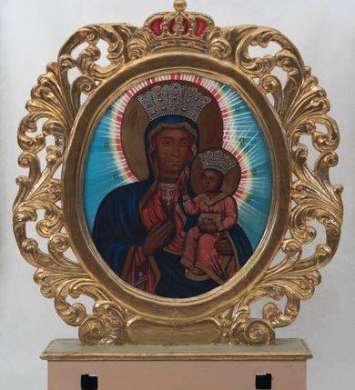 Zdjęcie nr 2: Pole obrazowe feretronu uzyskało kształt owalu ujętego w złoconą, ażurową ramę skomponowaną z liści akantu. Całość obramienia wieńczy zamknięta, korona z krzyżykiem na globie, wypełniona purpurą z obręczą naśladującą kameryzację. Na awersie w polu obrazowym feretronu przedstawiono Chrystusa Bolesnego w typie Ecce Homo. Postać ukazana została w półpostaci z głową lekko przechyloną w prawą stronę. Chrystus ma ręce związane w nadgarstkach. W prawej ręce trzyma trzcinę. Zarówno twarz, jak i tors otrzymały jasną karnację. Jego umęczone oblicze charakteryzuje prosty nos, szeroko otwarte oczy oraz wydatne, czerwone usta. Głowę okalają jasnobrązowe włosy, odsłaniające lewe ucho, które puklami opadają na ramiona. Wokół twarzy widoczny jest krótki zarost przechodzący w charakterystycznie zawiniętą podwójnie brodę. Na głowie ma małą koronę cierniową, spod której ciekną strużki krwi, widoczne na czole, skroniach, włosach, torsie i rękach. Chrystus na ramionach ma narzucony purpurowy płaszcz zakrywający prawe ramię, którego obie poły są zawinięte na wysokości skrępowanych dłoni. Jego postać otaczają delikatnie zaznaczone jasne promienie widoczne na jasnoniebieskim tle całego przedstawienia. Na rewersie pola obrazowego feretronu namalowano wizerunek Matki Boskiej Częstochowskiej. Madonna została ukazana frontalnie w półpostaci. Prawą ręką wskazuje na trzymane na lewym ramieniu Dzieciątko Jezus. Jej podłużną twarz o ciemnej karnacji charakteryzuje wydatny, prosty nos, migdałowe oczy, mięsiste usta oraz dwa równoległe cięcia widoczne na prawym policzku. Na głowie ma ciemnoniebieski maforion podbity czerwienią i lamowany ciemnoochrową taśmą, odsłaniający fragment szkarłatnej sukni na piersi oraz prawy jej rękaw. Pod szyją namalowano potrójny sznur pereł z zawieszonym na nim srebrnym krzyżykiem. Maria ma na głowie wysoką koronę o obłych sterczynach, dekorowaną imitacją pereł oraz kamieni szlachetnych. Dzieciątko zostało ujęte w trzech trzecich, z głową zwróconą w prawą stronę. Prawą rękę wznosi w geście błogosławieństwa, w lewej natomiast trzyma gruby kodeks Ewangelii w szkarłatnej okładce. Mały Jezus ma owalną twarz o ciemnej karnacji. Widoczny jest wydatny nos i usta oraz szeroko otwarte oczy. Ma na sobie szkarłatnoczerwoną tunikę zdobioną srebrnymi rozetkami i lamowaną ciemnoochrową grubą taśmą. Głowę Chrystusa wieńczy wysoka korona, kształtem i dekoracją zbliżona do korony Madonny. Głowy postaci otaczają złocistoochrowe nimby, poszerzone o czerwonożółty otok ze złotymi gwiazdami oraz dodatkowo malowane jasne promienie widoczne na jasnoniebieskim tle obrazu. 
