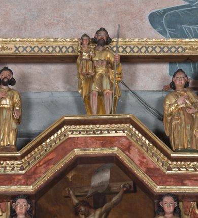 Zdjęcie nr 13: Ołtarz główny w Głębowicach otrzymał strukturę przyściennego, trójosiowego retabulum architektonicznego o dwóch kondygnacjach. Zaopatrzono go w predellę i zwieńczenie oraz dwa uszaki z boku zdobione herbem Starykoń i Jelita. Wisząc na ścianie wspiera się na dwóch masywnych, krótkich półkolumnach flankujących wejście do zakrystii. W środkowej części predelli widoczne jest wycięcie. Predellę po bokach ujmuje para konsoli wspierających wyłamujący się ponad nimi gzyms. Osie części środkowej nastawy ujęte są parami wolnostojących kolumn o kapitelach korynckich wspierających wyłamujące się ponad nimi belkowanie. Pole części środkowej nastawy ma kształt stojącego prostokąta zamkniętego nadwieszonym łukiem odcinkowym. Z kolei pola osi bocznych są artykułowane parą zamkniętych półkoliście niszy. Druga kondygnacja retabulum, będąca zarazem jego zwieńczeniem, została ujęta parą herm wspierających belkowanie przybierające formę łuku trójbocznego z ośmioboku. Po bokach widoczna jest para półkolistych, przerwanych przyczółków. Boki predelli ujęte zostały ulistnionymi wolutami, dodatkowo zdobionymi stylizowanymi motywami roślinno-kwiatowymi oraz motywem zwisu tkaniny z supłem. Konsole zdobione są liśćmi akantu oraz parą uskrzydlonych główek anielskich ze zwisami w formie pojedynczych kampanull. Po bokach predelli, na przedłużeniu zewnętrznych kolumn nastawy, podwieszono parę szyszek. Trzony kolumn zostały ozdobione w dolnej partii płaskorzeźbionymi, uskrzydlonymi główkami anielskimi, w górnej zewnętrzne – wicią winnej latorośli, zaś wewnętrzne motywem kandelabru. Osi boczne nastawy zostały ozdobione w dolnej partii ornamnetyką roślinną i parą główek anielskich ujętych motywami roślinnymi. Nisze dolnej kondygnacji wypełniono konchami, zdobionymi motywem ulistnionych rozetek. Z kolei trójboczne z ośmioboku konsole zostały ozdobione stylizowanymi liśćmi. W partii fryzu widoczna jest para mniejszych i większych uskrzydlonych główek anielskich. Drugą kondygnację - zwieńczenie, zostało ujęte parą herm z sylwetkami kobiecymi oraz parą uszaków o fantazyjnym wykroju z motywem maski lunarnej. Także fantazyjną formę z motywem głowy gryfa trzymającego w dziobie szarfę uzyskały uszaki w dolnej kondygnacji. W ich centrum widoczne są dwa owalne medaliony z herbem Starykoń i Jelita. W części środkowej nastawy znajduje się obraz Franciszka Lekszyckiego &quot;Matka Boska Szkaplerzna wręcza szkaplerz św. Szymonowi Stockowi&quot;. Na zasuwie obraz &quot;Matka Boska Różańcowa&quot;. Po bokach obrazu w niszach flankowanych kolumnami ustawiono rzeźbione wyobrażenie św. Marii Magdaleny i św. Katarzyny Aleksandryjskiej. W centrum drugiej kondygnacji-zwieńczeniu znajduje się obraz &quot;Św. Maria Magdalena przed Ukrzyżowanym Chrystusem&quot;. Po bokach, na przyczółkach znajduje się para rzeźbionych stojących aniołów trzymających w dłoniach kartusze o fantazyjnych wykrojach. W kartuszu z prawej strony widnieje napis: &quot;konserwacja 1973, 2016&quot;, a z lewej: &quot;sancta scapularis&quot;. Na szczycie ołtarza trzy rzeźbione przedstawienia - bo bokach św. Piotra i św. Jana Ewangelisty, a po środku św. Krzysztofa. Struktura nastawy jest marmoryzowana w odcieniach różu i ceglastej czerwieni. Partie detalu architektonicznego i ornamentyka są złocone i srebrzone.