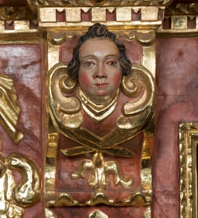 Zdjęcie nr 6: Ołtarz główny w Głębowicach otrzymał strukturę przyściennego, trójosiowego retabulum architektonicznego o dwóch kondygnacjach. Zaopatrzono go w predellę i zwieńczenie oraz dwa uszaki z boku zdobione herbem Starykoń i Jelita. Wisząc na ścianie wspiera się na dwóch masywnych, krótkich półkolumnach flankujących wejście do zakrystii. W środkowej części predelli widoczne jest wycięcie. Predellę po bokach ujmuje para konsoli wspierających wyłamujący się ponad nimi gzyms. Osie części środkowej nastawy ujęte są parami wolnostojących kolumn o kapitelach korynckich wspierających wyłamujące się ponad nimi belkowanie. Pole części środkowej nastawy ma kształt stojącego prostokąta zamkniętego nadwieszonym łukiem odcinkowym. Z kolei pola osi bocznych są artykułowane parą zamkniętych półkoliście niszy. Druga kondygnacja retabulum, będąca zarazem jego zwieńczeniem, została ujęta parą herm wspierających belkowanie przybierające formę łuku trójbocznego z ośmioboku. Po bokach widoczna jest para półkolistych, przerwanych przyczółków. Boki predelli ujęte zostały ulistnionymi wolutami, dodatkowo zdobionymi stylizowanymi motywami roślinno-kwiatowymi oraz motywem zwisu tkaniny z supłem. Konsole zdobione są liśćmi akantu oraz parą uskrzydlonych główek anielskich ze zwisami w formie pojedynczych kampanull. Po bokach predelli, na przedłużeniu zewnętrznych kolumn nastawy, podwieszono parę szyszek. Trzony kolumn zostały ozdobione w dolnej partii płaskorzeźbionymi, uskrzydlonymi główkami anielskimi, w górnej zewnętrzne – wicią winnej latorośli, zaś wewnętrzne motywem kandelabru. Osi boczne nastawy zostały ozdobione w dolnej partii ornamnetyką roślinną i parą główek anielskich ujętych motywami roślinnymi. Nisze dolnej kondygnacji wypełniono konchami, zdobionymi motywem ulistnionych rozetek. Z kolei trójboczne z ośmioboku konsole zostały ozdobione stylizowanymi liśćmi. W partii fryzu widoczna jest para mniejszych i większych uskrzydlonych główek anielskich. Drugą kondygnację - zwieńczenie, zostało ujęte parą herm z sylwetkami kobiecymi oraz parą uszaków o fantazyjnym wykroju z motywem maski lunarnej. Także fantazyjną formę z motywem głowy gryfa trzymającego w dziobie szarfę uzyskały uszaki w dolnej kondygnacji. W ich centrum widoczne są dwa owalne medaliony z herbem Starykoń i Jelita. W części środkowej nastawy znajduje się obraz Franciszka Lekszyckiego "Matka Boska Szkaplerzna wręcza szkaplerz św. Szymonowi Stockowi". Na zasuwie obraz "Matka Boska Różańcowa". Po bokach obrazu w niszach flankowanych kolumnami ustawiono rzeźbione wyobrażenie św. Marii Magdaleny i św. Katarzyny Aleksandryjskiej. W centrum drugiej kondygnacji-zwieńczeniu znajduje się obraz "Św. Maria Magdalena przed Ukrzyżowanym Chrystusem". Po bokach, na przyczółkach znajduje się para rzeźbionych stojących aniołów trzymających w dłoniach kartusze o fantazyjnych wykrojach. W kartuszu z prawej strony widnieje napis: "konserwacja 1973, 2016", a z lewej: "sancta scapularis". Na szczycie ołtarza trzy rzeźbione przedstawienia - bo bokach św. Piotra i św. Jana Ewangelisty, a po środku św. Krzysztofa. Struktura nastawy jest marmoryzowana w odcieniach różu i ceglastej czerwieni. Partie detalu architektonicznego i ornamentyka są złocone i srebrzone.