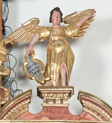 Zdjęcie nr 10: Ołtarz główny w Głębowicach otrzymał strukturę przyściennego, trójosiowego retabulum architektonicznego o dwóch kondygnacjach. Zaopatrzono go w predellę i zwieńczenie oraz dwa uszaki z boku zdobione herbem Starykoń i Jelita. Wisząc na ścianie wspiera się na dwóch masywnych, krótkich półkolumnach flankujących wejście do zakrystii. W środkowej części predelli widoczne jest wycięcie. Predellę po bokach ujmuje para konsoli wspierających wyłamujący się ponad nimi gzyms. Osie części środkowej nastawy ujęte są parami wolnostojących kolumn o kapitelach korynckich wspierających wyłamujące się ponad nimi belkowanie. Pole części środkowej nastawy ma kształt stojącego prostokąta zamkniętego nadwieszonym łukiem odcinkowym. Z kolei pola osi bocznych są artykułowane parą zamkniętych półkoliście niszy. Druga kondygnacja retabulum, będąca zarazem jego zwieńczeniem, została ujęta parą herm wspierających belkowanie przybierające formę łuku trójbocznego z ośmioboku. Po bokach widoczna jest para półkolistych, przerwanych przyczółków. Boki predelli ujęte zostały ulistnionymi wolutami, dodatkowo zdobionymi stylizowanymi motywami roślinno-kwiatowymi oraz motywem zwisu tkaniny z supłem. Konsole zdobione są liśćmi akantu oraz parą uskrzydlonych główek anielskich ze zwisami w formie pojedynczych kampanull. Po bokach predelli, na przedłużeniu zewnętrznych kolumn nastawy, podwieszono parę szyszek. Trzony kolumn zostały ozdobione w dolnej partii płaskorzeźbionymi, uskrzydlonymi główkami anielskimi, w górnej zewnętrzne – wicią winnej latorośli, zaś wewnętrzne motywem kandelabru. Osi boczne nastawy zostały ozdobione w dolnej partii ornamnetyką roślinną i parą główek anielskich ujętych motywami roślinnymi. Nisze dolnej kondygnacji wypełniono konchami, zdobionymi motywem ulistnionych rozetek. Z kolei trójboczne z ośmioboku konsole zostały ozdobione stylizowanymi liśćmi. W partii fryzu widoczna jest para mniejszych i większych uskrzydlonych główek anielskich. Drugą kondygnację - zwieńczenie, zostało ujęte parą herm z sylwetkami kobiecymi oraz parą uszaków o fantazyjnym wykroju z motywem maski lunarnej. Także fantazyjną formę z motywem głowy gryfa trzymającego w dziobie szarfę uzyskały uszaki w dolnej kondygnacji. W ich centrum widoczne są dwa owalne medaliony z herbem Starykoń i Jelita. W części środkowej nastawy znajduje się obraz Franciszka Lekszyckiego "Matka Boska Szkaplerzna wręcza szkaplerz św. Szymonowi Stockowi". Na zasuwie obraz "Matka Boska Różańcowa". Po bokach obrazu w niszach flankowanych kolumnami ustawiono rzeźbione wyobrażenie św. Marii Magdaleny i św. Katarzyny Aleksandryjskiej. W centrum drugiej kondygnacji-zwieńczeniu znajduje się obraz "Św. Maria Magdalena przed Ukrzyżowanym Chrystusem". Po bokach, na przyczółkach znajduje się para rzeźbionych stojących aniołów trzymających w dłoniach kartusze o fantazyjnych wykrojach. W kartuszu z prawej strony widnieje napis: "konserwacja 1973, 2016", a z lewej: "sancta scapularis". Na szczycie ołtarza trzy rzeźbione przedstawienia - bo bokach św. Piotra i św. Jana Ewangelisty, a po środku św. Krzysztofa. Struktura nastawy jest marmoryzowana w odcieniach różu i ceglastej czerwieni. Partie detalu architektonicznego i ornamentyka są złocone i srebrzone.