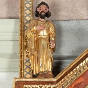 Zdjęcie nr 1: Rzeźbiona figura ukazuje całopostaciowe wyobrażenie stojącego frontalnie św. Jana Apostoła. Święty ma owalną, szeroką twarz o sumarycznym modelunku rysów i rumianych policzkach z krótkim, ciemnobrązowym zarostem. Jego brązowe włosy układają się w pukle założone za wydatne uszy. Apostoł ubrany jest w długą, złoconą przewiązaną w pasie tunikę z kołnierzykiem oraz złocony płaszcz. Prawą rękę wspiera na piersiach. Pierwotnie trzymał w niej kielich.