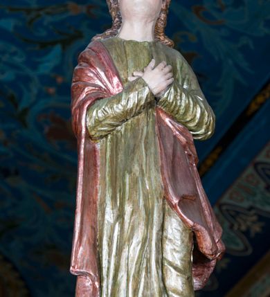 Zdjęcie nr 7: Grupa Ukrzyżowania składa się z pełnoplastycznych, całopostaciowych figur ustawionych na belce tęczowej. Pośrodku zamocowano polichromowany na ciemnobrązowo krzyż z realistycznie rzeźbioną figurą Chrystusa o plastycznie opracowanym modelunku muskulatury ciała. Postać do krzyża przytwierdzono za pomocą trzech gwoździ. Zbawiciel ma głowę pochyloną i złożoną na prawym barku. Posiada szeroką, owalną twarz o sumarycznie opracowanych rysach, półprzymknięte oczy, lekko rozchylone usta i krótki, ciemnobrązowy zarost. Długie, ciemnobrązowe, falowane włosy opadają mu na plecy i na prawy bark. Na głowie znajduje się zielona, cierniowa korona, spod której ciekną stróżki krwi. Nieproporcjonalnie długie ramiona ułożone zostały w płytkim, U-kształtnym zwisie z zaznaczonymi ścięgnami i żyłami na przedramionach. Dłonie o zaciśniętych palcach przybito dwoma gwoździami, spod których ciekną strużki krwi. Klatkę piersiową ukształtowano z wyraziście zaznaczoną linią żeber i raną w boku ze strugami krwi. Na biodrach umiejscowiono krótkie, złocone perizonium z festonem przy prawym boku. Jego zwichrowane draperie zostały ułożone horyzontalnie. Chrystus ma zgięte w kolanach nogi z założoną prawą stopą na lewą przybite jednym gwoździem. W górnej partii pionowej belki krzyża zawieszono biały titulus w formie banderoli z napisem: "INRI". 
U stóp krzyża, po lewej stronie, na niskiej, prostopadłościennej podstawie, ustawiono rzeźbę klęczącej św. Marii Magdaleny. Święta jest zwrócona profilem w prawo. Jej owalną twarz charakteryzują sumarycznie opracowane rysy. Ma długie brązowe, lekko falowane włosy opadające na plecy. Ubrana jest w długą, srebrzystobłękitną, drobno fałdowaną suknię związaną srebrnym paskiem. Oburącz ujmuje pionową belkę krzyża. Tuż obok niej, na lewo, na niskiej, prostopadłościennej podstawie ustawiono figurę stojącej frontalnie Matki Boskiej Bolesnej. Jej nieznacznie odchyloną głowę charakteryzuje owalna, szeroka twarz o sumarycznie opracowanych rysach i wzroku skierowanym ku górze. Maria ubrana jest w długą srebrzyścieczerwoną suknię przewiązaną złotym paskiem i osłaniający głowę, plecy i prawe ramię, drobnofałdowany srebrzysty płaszcz. Ręce trzyma złożone w geście modlitwy. Po prawej stronie krzyża na niskiej, prostopadłościennej podstawie zamocowano stojącą figurę św. Jana Ewangelisty, ujętego frontalnie w nieznacznym kontrapoście. Święty ma lekko odchyloną do tyłu, zwróconą w trzech czwartych w lewo głowę. Charakteryzuje ją owalna, szeroka twarz o sumarycznie opracowanych rysach. Na plecy opadają mu długie, falowane, brązowe włosy. Jan ubrany jest w długą, srebrzystozieloną tunikę i przerzucony przez prawe ramię i podtrzymywany lewym przedramieniem złocistoochrowy płaszcz. Ręce trzyma skrzyżowane na piersiach. Z tyłu titulusa widnieje napis: Malował Jan i Ludwik, bracia Stankiewicze 1913. Napis widoczny jest także na górnej płaszczyźnie z tyłu krzyża: Malował 1913. 
Belka tęczowa jest prostopadłościenna, o profilowanych dolnych narożach. Polichromowano ją w odcieniach zieleni, czerwieni i żółci. Na środku widnieje flankowany parą złoconych krzyżyków złocony z przodu napis: + OTO BARANEK BOŻY KTÓRY GŁADZI GRZECHY ŚWIATA +; z tyłu: RENOVATUM A[nno] D[omini] 1913 + 1953 + 1983 + 2013