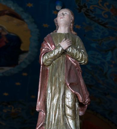 Zdjęcie nr 5: Grupa Ukrzyżowania składa się z pełnoplastycznych, całopostaciowych figur ustawionych na belce tęczowej. Pośrodku zamocowano polichromowany na ciemnobrązowo krzyż z realistycznie rzeźbioną figurą Chrystusa o plastycznie opracowanym modelunku muskulatury ciała. Postać do krzyża przytwierdzono za pomocą trzech gwoździ. Zbawiciel ma głowę pochyloną i złożoną na prawym barku. Posiada szeroką, owalną twarz o sumarycznie opracowanych rysach, półprzymknięte oczy, lekko rozchylone usta i krótki, ciemnobrązowy zarost. Długie, ciemnobrązowe, falowane włosy opadają mu na plecy i na prawy bark. Na głowie znajduje się zielona, cierniowa korona, spod której ciekną stróżki krwi. Nieproporcjonalnie długie ramiona ułożone zostały w płytkim, U-kształtnym zwisie z zaznaczonymi ścięgnami i żyłami na przedramionach. Dłonie o zaciśniętych palcach przybito dwoma gwoździami, spod których ciekną strużki krwi. Klatkę piersiową ukształtowano z wyraziście zaznaczoną linią żeber i raną w boku ze strugami krwi. Na biodrach umiejscowiono krótkie, złocone perizonium z festonem przy prawym boku. Jego zwichrowane draperie zostały ułożone horyzontalnie. Chrystus ma zgięte w kolanach nogi z założoną prawą stopą na lewą przybite jednym gwoździem. W górnej partii pionowej belki krzyża zawieszono biały titulus w formie banderoli z napisem: "INRI". 
U stóp krzyża, po lewej stronie, na niskiej, prostopadłościennej podstawie, ustawiono rzeźbę klęczącej św. Marii Magdaleny. Święta jest zwrócona profilem w prawo. Jej owalną twarz charakteryzują sumarycznie opracowane rysy. Ma długie brązowe, lekko falowane włosy opadające na plecy. Ubrana jest w długą, srebrzystobłękitną, drobno fałdowaną suknię związaną srebrnym paskiem. Oburącz ujmuje pionową belkę krzyża. Tuż obok niej, na lewo, na niskiej, prostopadłościennej podstawie ustawiono figurę stojącej frontalnie Matki Boskiej Bolesnej. Jej nieznacznie odchyloną głowę charakteryzuje owalna, szeroka twarz o sumarycznie opracowanych rysach i wzroku skierowanym ku górze. Maria ubrana jest w długą srebrzyścieczerwoną suknię przewiązaną złotym paskiem i osłaniający głowę, plecy i prawe ramię, drobnofałdowany srebrzysty płaszcz. Ręce trzyma złożone w geście modlitwy. Po prawej stronie krzyża na niskiej, prostopadłościennej podstawie zamocowano stojącą figurę św. Jana Ewangelisty, ujętego frontalnie w nieznacznym kontrapoście. Święty ma lekko odchyloną do tyłu, zwróconą w trzech czwartych w lewo głowę. Charakteryzuje ją owalna, szeroka twarz o sumarycznie opracowanych rysach. Na plecy opadają mu długie, falowane, brązowe włosy. Jan ubrany jest w długą, srebrzystozieloną tunikę i przerzucony przez prawe ramię i podtrzymywany lewym przedramieniem złocistoochrowy płaszcz. Ręce trzyma skrzyżowane na piersiach. Z tyłu titulusa widnieje napis: Malował Jan i Ludwik, bracia Stankiewicze 1913. Napis widoczny jest także na górnej płaszczyźnie z tyłu krzyża: Malował 1913. 
Belka tęczowa jest prostopadłościenna, o profilowanych dolnych narożach. Polichromowano ją w odcieniach zieleni, czerwieni i żółci. Na środku widnieje flankowany parą złoconych krzyżyków złocony z przodu napis: + OTO BARANEK BOŻY KTÓRY GŁADZI GRZECHY ŚWIATA +; z tyłu: RENOVATUM A[nno] D[omini] 1913 + 1953 + 1983 + 2013