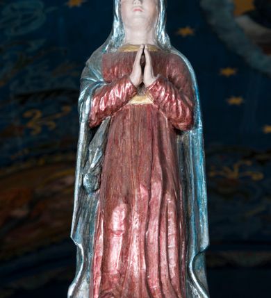 Zdjęcie nr 17: Grupa Ukrzyżowania składa się z pełnoplastycznych, całopostaciowych figur ustawionych na belce tęczowej. Pośrodku zamocowano polichromowany na ciemnobrązowo krzyż z realistycznie rzeźbioną figurą Chrystusa o plastycznie opracowanym modelunku muskulatury ciała. Postać do krzyża przytwierdzono za pomocą trzech gwoździ. Zbawiciel ma głowę pochyloną i złożoną na prawym barku. Posiada szeroką, owalną twarz o sumarycznie opracowanych rysach, półprzymknięte oczy, lekko rozchylone usta i krótki, ciemnobrązowy zarost. Długie, ciemnobrązowe, falowane włosy opadają mu na plecy i na prawy bark. Na głowie znajduje się zielona, cierniowa korona, spod której ciekną stróżki krwi. Nieproporcjonalnie długie ramiona ułożone zostały w płytkim, U-kształtnym zwisie z zaznaczonymi ścięgnami i żyłami na przedramionach. Dłonie o zaciśniętych palcach przybito dwoma gwoździami, spod których ciekną strużki krwi. Klatkę piersiową ukształtowano z wyraziście zaznaczoną linią żeber i raną w boku ze strugami krwi. Na biodrach umiejscowiono krótkie, złocone perizonium z festonem przy prawym boku. Jego zwichrowane draperie zostały ułożone horyzontalnie. Chrystus ma zgięte w kolanach nogi z założoną prawą stopą na lewą przybite jednym gwoździem. W górnej partii pionowej belki krzyża zawieszono biały titulus w formie banderoli z napisem: "INRI". 
U stóp krzyża, po lewej stronie, na niskiej, prostopadłościennej podstawie, ustawiono rzeźbę klęczącej św. Marii Magdaleny. Święta jest zwrócona profilem w prawo. Jej owalną twarz charakteryzują sumarycznie opracowane rysy. Ma długie brązowe, lekko falowane włosy opadające na plecy. Ubrana jest w długą, srebrzystobłękitną, drobno fałdowaną suknię związaną srebrnym paskiem. Oburącz ujmuje pionową belkę krzyża. Tuż obok niej, na lewo, na niskiej, prostopadłościennej podstawie ustawiono figurę stojącej frontalnie Matki Boskiej Bolesnej. Jej nieznacznie odchyloną głowę charakteryzuje owalna, szeroka twarz o sumarycznie opracowanych rysach i wzroku skierowanym ku górze. Maria ubrana jest w długą srebrzyścieczerwoną suknię przewiązaną złotym paskiem i osłaniający głowę, plecy i prawe ramię, drobnofałdowany srebrzysty płaszcz. Ręce trzyma złożone w geście modlitwy. Po prawej stronie krzyża na niskiej, prostopadłościennej podstawie zamocowano stojącą figurę św. Jana Ewangelisty, ujętego frontalnie w nieznacznym kontrapoście. Święty ma lekko odchyloną do tyłu, zwróconą w trzech czwartych w lewo głowę. Charakteryzuje ją owalna, szeroka twarz o sumarycznie opracowanych rysach. Na plecy opadają mu długie, falowane, brązowe włosy. Jan ubrany jest w długą, srebrzystozieloną tunikę i przerzucony przez prawe ramię i podtrzymywany lewym przedramieniem złocistoochrowy płaszcz. Ręce trzyma skrzyżowane na piersiach. Z tyłu titulusa widnieje napis: Malował Jan i Ludwik, bracia Stankiewicze 1913. Napis widoczny jest także na górnej płaszczyźnie z tyłu krzyża: Malował 1913. 
Belka tęczowa jest prostopadłościenna, o profilowanych dolnych narożach. Polichromowano ją w odcieniach zieleni, czerwieni i żółci. Na środku widnieje flankowany parą złoconych krzyżyków złocony z przodu napis: + OTO BARANEK BOŻY KTÓRY GŁADZI GRZECHY ŚWIATA +; z tyłu: RENOVATUM A[nno] D[omini] 1913 + 1953 + 1983 + 2013