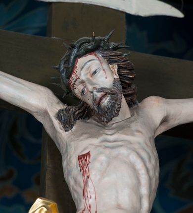 Zdjęcie nr 16: Grupa Ukrzyżowania składa się z pełnoplastycznych, całopostaciowych figur ustawionych na belce tęczowej. Pośrodku zamocowano polichromowany na ciemnobrązowo krzyż z realistycznie rzeźbioną figurą Chrystusa o plastycznie opracowanym modelunku muskulatury ciała. Postać do krzyża przytwierdzono za pomocą trzech gwoździ. Zbawiciel ma głowę pochyloną i złożoną na prawym barku. Posiada szeroką, owalną twarz o sumarycznie opracowanych rysach, półprzymknięte oczy, lekko rozchylone usta i krótki, ciemnobrązowy zarost. Długie, ciemnobrązowe, falowane włosy opadają mu na plecy i na prawy bark. Na głowie znajduje się zielona, cierniowa korona, spod której ciekną stróżki krwi. Nieproporcjonalnie długie ramiona ułożone zostały w płytkim, U-kształtnym zwisie z zaznaczonymi ścięgnami i żyłami na przedramionach. Dłonie o zaciśniętych palcach przybito dwoma gwoździami, spod których ciekną strużki krwi. Klatkę piersiową ukształtowano z wyraziście zaznaczoną linią żeber i raną w boku ze strugami krwi. Na biodrach umiejscowiono krótkie, złocone perizonium z festonem przy prawym boku. Jego zwichrowane draperie zostały ułożone horyzontalnie. Chrystus ma zgięte w kolanach nogi z założoną prawą stopą na lewą przybite jednym gwoździem. W górnej partii pionowej belki krzyża zawieszono biały titulus w formie banderoli z napisem: "INRI". 
U stóp krzyża, po lewej stronie, na niskiej, prostopadłościennej podstawie, ustawiono rzeźbę klęczącej św. Marii Magdaleny. Święta jest zwrócona profilem w prawo. Jej owalną twarz charakteryzują sumarycznie opracowane rysy. Ma długie brązowe, lekko falowane włosy opadające na plecy. Ubrana jest w długą, srebrzystobłękitną, drobno fałdowaną suknię związaną srebrnym paskiem. Oburącz ujmuje pionową belkę krzyża. Tuż obok niej, na lewo, na niskiej, prostopadłościennej podstawie ustawiono figurę stojącej frontalnie Matki Boskiej Bolesnej. Jej nieznacznie odchyloną głowę charakteryzuje owalna, szeroka twarz o sumarycznie opracowanych rysach i wzroku skierowanym ku górze. Maria ubrana jest w długą srebrzyścieczerwoną suknię przewiązaną złotym paskiem i osłaniający głowę, plecy i prawe ramię, drobnofałdowany srebrzysty płaszcz. Ręce trzyma złożone w geście modlitwy. Po prawej stronie krzyża na niskiej, prostopadłościennej podstawie zamocowano stojącą figurę św. Jana Ewangelisty, ujętego frontalnie w nieznacznym kontrapoście. Święty ma lekko odchyloną do tyłu, zwróconą w trzech czwartych w lewo głowę. Charakteryzuje ją owalna, szeroka twarz o sumarycznie opracowanych rysach. Na plecy opadają mu długie, falowane, brązowe włosy. Jan ubrany jest w długą, srebrzystozieloną tunikę i przerzucony przez prawe ramię i podtrzymywany lewym przedramieniem złocistoochrowy płaszcz. Ręce trzyma skrzyżowane na piersiach. Z tyłu titulusa widnieje napis: Malował Jan i Ludwik, bracia Stankiewicze 1913. Napis widoczny jest także na górnej płaszczyźnie z tyłu krzyża: Malował 1913. 
Belka tęczowa jest prostopadłościenna, o profilowanych dolnych narożach. Polichromowano ją w odcieniach zieleni, czerwieni i żółci. Na środku widnieje flankowany parą złoconych krzyżyków złocony z przodu napis: + OTO BARANEK BOŻY KTÓRY GŁADZI GRZECHY ŚWIATA +; z tyłu: RENOVATUM A[nno] D[omini] 1913 + 1953 + 1983 + 2013