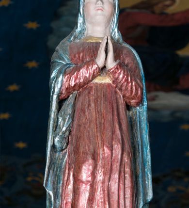 Zdjęcie nr 18: Grupa Ukrzyżowania składa się z pełnoplastycznych, całopostaciowych figur ustawionych na belce tęczowej. Pośrodku zamocowano polichromowany na ciemnobrązowo krzyż z realistycznie rzeźbioną figurą Chrystusa o plastycznie opracowanym modelunku muskulatury ciała. Postać do krzyża przytwierdzono za pomocą trzech gwoździ. Zbawiciel ma głowę pochyloną i złożoną na prawym barku. Posiada szeroką, owalną twarz o sumarycznie opracowanych rysach, półprzymknięte oczy, lekko rozchylone usta i krótki, ciemnobrązowy zarost. Długie, ciemnobrązowe, falowane włosy opadają mu na plecy i na prawy bark. Na głowie znajduje się zielona, cierniowa korona, spod której ciekną stróżki krwi. Nieproporcjonalnie długie ramiona ułożone zostały w płytkim, U-kształtnym zwisie z zaznaczonymi ścięgnami i żyłami na przedramionach. Dłonie o zaciśniętych palcach przybito dwoma gwoździami, spod których ciekną strużki krwi. Klatkę piersiową ukształtowano z wyraziście zaznaczoną linią żeber i raną w boku ze strugami krwi. Na biodrach umiejscowiono krótkie, złocone perizonium z festonem przy prawym boku. Jego zwichrowane draperie zostały ułożone horyzontalnie. Chrystus ma zgięte w kolanach nogi z założoną prawą stopą na lewą przybite jednym gwoździem. W górnej partii pionowej belki krzyża zawieszono biały titulus w formie banderoli z napisem: "INRI". 
U stóp krzyża, po lewej stronie, na niskiej, prostopadłościennej podstawie, ustawiono rzeźbę klęczącej św. Marii Magdaleny. Święta jest zwrócona profilem w prawo. Jej owalną twarz charakteryzują sumarycznie opracowane rysy. Ma długie brązowe, lekko falowane włosy opadające na plecy. Ubrana jest w długą, srebrzystobłękitną, drobno fałdowaną suknię związaną srebrnym paskiem. Oburącz ujmuje pionową belkę krzyża. Tuż obok niej, na lewo, na niskiej, prostopadłościennej podstawie ustawiono figurę stojącej frontalnie Matki Boskiej Bolesnej. Jej nieznacznie odchyloną głowę charakteryzuje owalna, szeroka twarz o sumarycznie opracowanych rysach i wzroku skierowanym ku górze. Maria ubrana jest w długą srebrzyścieczerwoną suknię przewiązaną złotym paskiem i osłaniający głowę, plecy i prawe ramię, drobnofałdowany srebrzysty płaszcz. Ręce trzyma złożone w geście modlitwy. Po prawej stronie krzyża na niskiej, prostopadłościennej podstawie zamocowano stojącą figurę św. Jana Ewangelisty, ujętego frontalnie w nieznacznym kontrapoście. Święty ma lekko odchyloną do tyłu, zwróconą w trzech czwartych w lewo głowę. Charakteryzuje ją owalna, szeroka twarz o sumarycznie opracowanych rysach. Na plecy opadają mu długie, falowane, brązowe włosy. Jan ubrany jest w długą, srebrzystozieloną tunikę i przerzucony przez prawe ramię i podtrzymywany lewym przedramieniem złocistoochrowy płaszcz. Ręce trzyma skrzyżowane na piersiach. Z tyłu titulusa widnieje napis: Malował Jan i Ludwik, bracia Stankiewicze 1913. Napis widoczny jest także na górnej płaszczyźnie z tyłu krzyża: Malował 1913. 
Belka tęczowa jest prostopadłościenna, o profilowanych dolnych narożach. Polichromowano ją w odcieniach zieleni, czerwieni i żółci. Na środku widnieje flankowany parą złoconych krzyżyków złocony z przodu napis: + OTO BARANEK BOŻY KTÓRY GŁADZI GRZECHY ŚWIATA +; z tyłu: RENOVATUM A[nno] D[omini] 1913 + 1953 + 1983 + 2013