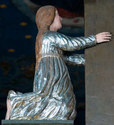 Zdjęcie nr 10: Grupa Ukrzyżowania składa się z pełnoplastycznych, całopostaciowych figur ustawionych na belce tęczowej. Pośrodku zamocowano polichromowany na ciemnobrązowo krzyż z realistycznie rzeźbioną figurą Chrystusa o plastycznie opracowanym modelunku muskulatury ciała. Postać do krzyża przytwierdzono za pomocą trzech gwoździ. Zbawiciel ma głowę pochyloną i złożoną na prawym barku. Posiada szeroką, owalną twarz o sumarycznie opracowanych rysach, półprzymknięte oczy, lekko rozchylone usta i krótki, ciemnobrązowy zarost. Długie, ciemnobrązowe, falowane włosy opadają mu na plecy i na prawy bark. Na głowie znajduje się zielona, cierniowa korona, spod której ciekną stróżki krwi. Nieproporcjonalnie długie ramiona ułożone zostały w płytkim, U-kształtnym zwisie z zaznaczonymi ścięgnami i żyłami na przedramionach. Dłonie o zaciśniętych palcach przybito dwoma gwoździami, spod których ciekną strużki krwi. Klatkę piersiową ukształtowano z wyraziście zaznaczoną linią żeber i raną w boku ze strugami krwi. Na biodrach umiejscowiono krótkie, złocone perizonium z festonem przy prawym boku. Jego zwichrowane draperie zostały ułożone horyzontalnie. Chrystus ma zgięte w kolanach nogi z założoną prawą stopą na lewą przybite jednym gwoździem. W górnej partii pionowej belki krzyża zawieszono biały titulus w formie banderoli z napisem: "INRI". 
U stóp krzyża, po lewej stronie, na niskiej, prostopadłościennej podstawie, ustawiono rzeźbę klęczącej św. Marii Magdaleny. Święta jest zwrócona profilem w prawo. Jej owalną twarz charakteryzują sumarycznie opracowane rysy. Ma długie brązowe, lekko falowane włosy opadające na plecy. Ubrana jest w długą, srebrzystobłękitną, drobno fałdowaną suknię związaną srebrnym paskiem. Oburącz ujmuje pionową belkę krzyża. Tuż obok niej, na lewo, na niskiej, prostopadłościennej podstawie ustawiono figurę stojącej frontalnie Matki Boskiej Bolesnej. Jej nieznacznie odchyloną głowę charakteryzuje owalna, szeroka twarz o sumarycznie opracowanych rysach i wzroku skierowanym ku górze. Maria ubrana jest w długą srebrzyścieczerwoną suknię przewiązaną złotym paskiem i osłaniający głowę, plecy i prawe ramię, drobnofałdowany srebrzysty płaszcz. Ręce trzyma złożone w geście modlitwy. Po prawej stronie krzyża na niskiej, prostopadłościennej podstawie zamocowano stojącą figurę św. Jana Ewangelisty, ujętego frontalnie w nieznacznym kontrapoście. Święty ma lekko odchyloną do tyłu, zwróconą w trzech czwartych w lewo głowę. Charakteryzuje ją owalna, szeroka twarz o sumarycznie opracowanych rysach. Na plecy opadają mu długie, falowane, brązowe włosy. Jan ubrany jest w długą, srebrzystozieloną tunikę i przerzucony przez prawe ramię i podtrzymywany lewym przedramieniem złocistoochrowy płaszcz. Ręce trzyma skrzyżowane na piersiach. Z tyłu titulusa widnieje napis: Malował Jan i Ludwik, bracia Stankiewicze 1913. Napis widoczny jest także na górnej płaszczyźnie z tyłu krzyża: Malował 1913. 
Belka tęczowa jest prostopadłościenna, o profilowanych dolnych narożach. Polichromowano ją w odcieniach zieleni, czerwieni i żółci. Na środku widnieje flankowany parą złoconych krzyżyków złocony z przodu napis: + OTO BARANEK BOŻY KTÓRY GŁADZI GRZECHY ŚWIATA +; z tyłu: RENOVATUM A[nno] D[omini] 1913 + 1953 + 1983 + 2013