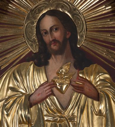 Zdjęcie nr 1: Obraz z wizerunkiem Najświętszego Serca Jezusa jest w kształcie stojącego prostokąta, od góry zamkniętego łukiem półkolistym, z górnymi narożnikami zaakcentowanymi przez wklęsłe łuki odcinkowe. Jezus został ukazany w półpostaci, niemal na wprost, głowę lekko przechyla w prawo. Pociągłą twarz charakteryzują delikatne rysy, długi prosty nos i krótki, ciemnobrązowy zarost. Długie, ciemnobrązowe, z przedziałkiem pośrodku, skręcone na końcach włosy opadają na ramiona. Dalsze elementy przedstawienia wydobyte są w obrębie partii złoconej sukienki: sylwetkę Jezusa osłania przewiązana pośrodku w pasie suknia o głęboko rozchylonym dekolcie; na ramiona narzucony jest płaszcz; dłońmi z ranami po gwoździach Jezus wskazuje na gorejące serce; jego głowę otacza nimb z wieńcem promieni. Tło jest jednolite, ciemnobordowe. Obraz ujęty jest profilowaną, złoconą ramą.