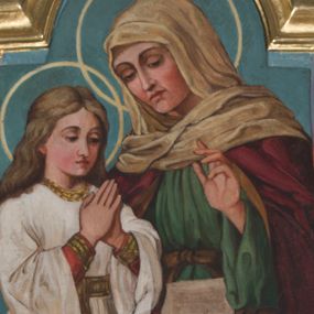 Zdjęcie nr 1: Pole obrazowe o lekko wklęsłych bokach i podstawie oraz ściętych dolnych narożach, zamknięte półkolistym łukiem nadwieszonym, ujęte profilowaną, złoconą ramą. W środku przedstawienie św. Anny nauczającej Marię. Po prawej stronie kompozycji siedząca en face, w ujęciu do kolan postać św. Anny. Lekko pochylona głowa w trzech czwartych zwrócona w lewo. Pociągłą twarz charakteryzują subtelne, wyraziste rysy. Na głowie biała chusta osłaniająca barki i szyję. Anna ubrana w zieloną, przewiązaną w pasie suknię z szerokimi rękawami oraz osłaniający plecy, ramiona i nogi ciemnoczerwony płaszcz. Lewą rękę unosi w geście przemowy (bądź "traditio"). Na kolanach otwarta księga. Po lewej stronie stojąca Maria zwrócona w trzech czwartych w prawo. Głowa nieznacznie pochylona. Zaokrągloną twarz charakteryzują delikatne rysy. Długie, falowane, jasnobrązowe włosy opadają na plecy. Ubrana w spodnią, czerwoną suknię z długimi, wąskimi rękawami obszytymi dekoracyjnymi galonami oraz wierzchnią, białą z długimi, szerokimi rękawami, dekoracyjnym obszyciem dekoltu, przewiązaną ozdobnym pasem. Ręce złożone w geście modlitewnym. Wokół głów postaci jasnożółte aureole. Tło jednolite, niebieskie.