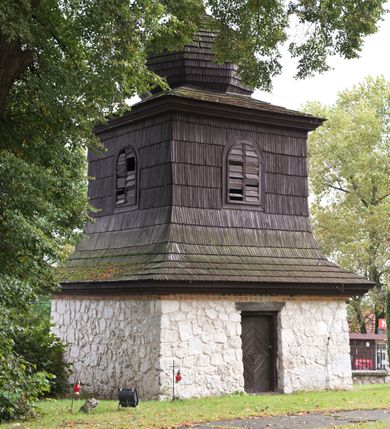 Zdjęcie nr 104: Kościół orientowany, murowany, jednonawowy z węższym prezbiterium zakończonym półkolistą absydą. Przy prezbiterium od północy znajduje się zakrystia, od południa kwadratowa kaplica św. Anny, a przy nawie od południa kruchta. Wnętrze kościoła nakryte jest nowym stropem, natomiast w kaplicy znajduje się sklepienie krzyżowo-żebrowe. Fasada zachodnia ujęta jest na narożnikach skośnymi szkarpami i zwieńczona schodkowym szczytem, podobnie zwieńczona jest kruchta południowa. Portal zachodni kamienny, z belkowaniem wspartym na dwóch liściastych konsolach ponad którymi edikula z płaskorzeźbionym krucyfiksem i klęczącymi postaciami męskimi. Na belkowaniu znajdują się dwa kartusze z herbami: po lewej herb Bończa, a nad nim litery „I” oraz „T”, a na prawo herb Szreniawa i litery „B” i „T”. Portal kruchty południowej jest również kamienny, podobny do zachodniego z inskrypcją: „IN LAVDEM ET GL[ORI]AM DEI O[MN]IP[OTENTIS] HO[NO]RE[M] / B(EATE) M(ARIAE) S(ANCTAE) V(IRGINIS) S(ANCTUS) AEGIDY ET OM(NIUM) SS. FIR. REGNÃTE [TERTIO] SIGISM[UN]DO / REGE POL[ONIAE] Z[?] HEMO[?] EP[ISCOP]O CRAC(OVIENSIS) BERN[AR]DO MACIEIOWSKI / NOVIT[ER] CAR[DINA]LI CRA[COVIENSE] DEI FACTO INTERI[M] PLEBA[N]O R[E]V[EREN]DO SEB(ASTIANO) / NAGRODIO A I SYRADIA PHI[LOSOPHI]AE DOCTORE COLLEG[I]A [MA]IORE / S. T(HEOLOGIAE) PVBLICO PROFES(SORE) PRAEP[OSI]TO S(ANCTA) AN(NAE) CRAC[OVIAE] DECIMARVM / ET FVNDI ECCL(ESIA)E HVIVS P[OST] IVRIS STREPITV(M) RESTITV / TORE ANNO OCTAVO PLEBANAT[U]S SVI. TEMPLVM HO(C) / [ dwa wiersze skute] DE' / NOWO AEDIFICATVM. ET. CONSTRVCTVM. ADIVTORIO / QVORVNDÃ ANNO D[OMINI] MDCIIII MENSE SEPTEMB[RE]”. Od południa świątyni umieszczone są trzy otwory okienne w kształcie stojących prostokątów, zamkniętych łukiem półkolistym, a w prezbiterium dwa małe okrągłe okna. Kościół nakryty jest dwoma dwuspadowymi dachami, nad prezbiterium nieco niższym, nad nawą zwieńczonym wąską i wysoką sygnaturką na dzwon. Wewnątrz świątyni na skrzyżowaniu nawy i prezbiterium umocowana jest drewniana belka tęczowa z ustawionym na niej krucyfiksem i figurami Matki Boskiej i św. Jana Ewangelisty. Chór zachodni drewniany, na planie prostokąta, pośrodku półkoliście zamknięty, wsparty na sześciu filarach, od północnego zachodu z obudowaną boazerią klatką schodową. 