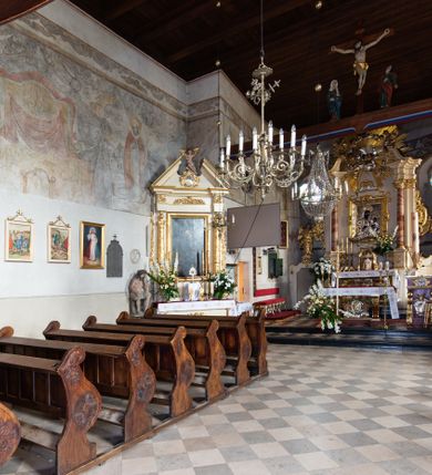 Zdjęcie nr 84: Kościół orientowany, murowany, jednonawowy z węższym prezbiterium zakończonym półkolistą absydą. Przy prezbiterium od północy znajduje się zakrystia, od południa kwadratowa kaplica św. Anny, a przy nawie od południa kruchta. Wnętrze kościoła nakryte jest nowym stropem, natomiast w kaplicy znajduje się sklepienie krzyżowo-żebrowe. Fasada zachodnia ujęta jest na narożnikach skośnymi szkarpami i zwieńczona schodkowym szczytem, podobnie zwieńczona jest kruchta południowa. Portal zachodni kamienny, z belkowaniem wspartym na dwóch liściastych konsolach ponad którymi edikula z płaskorzeźbionym krucyfiksem i klęczącymi postaciami męskimi. Na belkowaniu znajdują się dwa kartusze z herbami: po lewej herb Bończa, a nad nim litery „I” oraz „T”, a na prawo herb Szreniawa i litery „B” i „T”. Portal kruchty południowej jest również kamienny, podobny do zachodniego z inskrypcją: „IN LAVDEM ET GL[ORI]AM DEI O[MN]IP[OTENTIS] HO[NO]RE[M] / B(EATE) M(ARIAE) S(ANCTAE) V(IRGINIS) S(ANCTUS) AEGIDY ET OM(NIUM) SS. FIR. REGNÃTE [TERTIO] SIGISM[UN]DO / REGE POL[ONIAE] Z[?] HEMO[?] EP[ISCOP]O CRAC(OVIENSIS) BERN[AR]DO MACIEIOWSKI / NOVIT[ER] CAR[DINA]LI CRA[COVIENSE] DEI FACTO INTERI[M] PLEBA[N]O R[E]V[EREN]DO SEB(ASTIANO) / NAGRODIO A I SYRADIA PHI[LOSOPHI]AE DOCTORE COLLEG[I]A [MA]IORE / S. T(HEOLOGIAE) PVBLICO PROFES(SORE) PRAEP[OSI]TO S(ANCTA) AN(NAE) CRAC[OVIAE] DECIMARVM / ET FVNDI ECCL(ESIA)E HVIVS P[OST] IVRIS STREPITV(M) RESTITV / TORE ANNO OCTAVO PLEBANAT[U]S SVI. TEMPLVM HO(C) / [ dwa wiersze skute] DE' / NOWO AEDIFICATVM. ET. CONSTRVCTVM. ADIVTORIO / QVORVNDÃ ANNO D[OMINI] MDCIIII MENSE SEPTEMB[RE]”. Od południa świątyni umieszczone są trzy otwory okienne w kształcie stojących prostokątów, zamkniętych łukiem półkolistym, a w prezbiterium dwa małe okrągłe okna. Kościół nakryty jest dwoma dwuspadowymi dachami, nad prezbiterium nieco niższym, nad nawą zwieńczonym wąską i wysoką sygnaturką na dzwon. Wewnątrz świątyni na skrzyżowaniu nawy i prezbiterium umocowana jest drewniana belka tęczowa z ustawionym na niej krucyfiksem i figurami Matki Boskiej i św. Jana Ewangelisty. Chór zachodni drewniany, na planie prostokąta, pośrodku półkoliście zamknięty, wsparty na sześciu filarach, od północnego zachodu z obudowaną boazerią klatką schodową. 