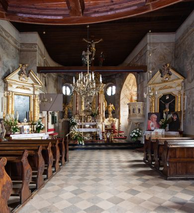 Zdjęcie nr 79: Kościół orientowany, murowany, jednonawowy z węższym prezbiterium zakończonym półkolistą absydą. Przy prezbiterium od północy znajduje się zakrystia, od południa kwadratowa kaplica św. Anny, a przy nawie od południa kruchta. Wnętrze kościoła nakryte jest nowym stropem, natomiast w kaplicy znajduje się sklepienie krzyżowo-żebrowe. Fasada zachodnia ujęta jest na narożnikach skośnymi szkarpami i zwieńczona schodkowym szczytem, podobnie zwieńczona jest kruchta południowa. Portal zachodni kamienny, z belkowaniem wspartym na dwóch liściastych konsolach ponad którymi edikula z płaskorzeźbionym krucyfiksem i klęczącymi postaciami męskimi. Na belkowaniu znajdują się dwa kartusze z herbami: po lewej herb Bończa, a nad nim litery „I” oraz „T”, a na prawo herb Szreniawa i litery „B” i „T”. Portal kruchty południowej jest również kamienny, podobny do zachodniego z inskrypcją: „IN LAVDEM ET GL[ORI]AM DEI O[MN]IP[OTENTIS] HO[NO]RE[M] / B(EATE) M(ARIAE) S(ANCTAE) V(IRGINIS) S(ANCTUS) AEGIDY ET OM(NIUM) SS. FIR. REGNÃTE [TERTIO] SIGISM[UN]DO / REGE POL[ONIAE] Z[?] HEMO[?] EP[ISCOP]O CRAC(OVIENSIS) BERN[AR]DO MACIEIOWSKI / NOVIT[ER] CAR[DINA]LI CRA[COVIENSE] DEI FACTO INTERI[M] PLEBA[N]O R[E]V[EREN]DO SEB(ASTIANO) / NAGRODIO A I SYRADIA PHI[LOSOPHI]AE DOCTORE COLLEG[I]A [MA]IORE / S. T(HEOLOGIAE) PVBLICO PROFES(SORE) PRAEP[OSI]TO S(ANCTA) AN(NAE) CRAC[OVIAE] DECIMARVM / ET FVNDI ECCL(ESIA)E HVIVS P[OST] IVRIS STREPITV(M) RESTITV / TORE ANNO OCTAVO PLEBANAT[U]S SVI. TEMPLVM HO(C) / [ dwa wiersze skute] DE' / NOWO AEDIFICATVM. ET. CONSTRVCTVM. ADIVTORIO / QVORVNDÃ ANNO D[OMINI] MDCIIII MENSE SEPTEMB[RE]”. Od południa świątyni umieszczone są trzy otwory okienne w kształcie stojących prostokątów, zamkniętych łukiem półkolistym, a w prezbiterium dwa małe okrągłe okna. Kościół nakryty jest dwoma dwuspadowymi dachami, nad prezbiterium nieco niższym, nad nawą zwieńczonym wąską i wysoką sygnaturką na dzwon. Wewnątrz świątyni na skrzyżowaniu nawy i prezbiterium umocowana jest drewniana belka tęczowa z ustawionym na niej krucyfiksem i figurami Matki Boskiej i św. Jana Ewangelisty. Chór zachodni drewniany, na planie prostokąta, pośrodku półkoliście zamknięty, wsparty na sześciu filarach, od północnego zachodu z obudowaną boazerią klatką schodową. 