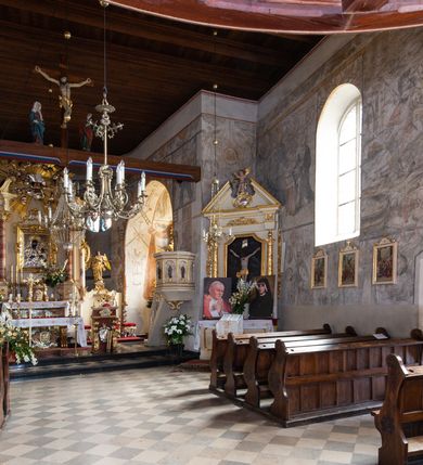 Zdjęcie nr 83: Kościół orientowany, murowany, jednonawowy z węższym prezbiterium zakończonym półkolistą absydą. Przy prezbiterium od północy znajduje się zakrystia, od południa kwadratowa kaplica św. Anny, a przy nawie od południa kruchta. Wnętrze kościoła nakryte jest nowym stropem, natomiast w kaplicy znajduje się sklepienie krzyżowo-żebrowe. Fasada zachodnia ujęta jest na narożnikach skośnymi szkarpami i zwieńczona schodkowym szczytem, podobnie zwieńczona jest kruchta południowa. Portal zachodni kamienny, z belkowaniem wspartym na dwóch liściastych konsolach ponad którymi edikula z płaskorzeźbionym krucyfiksem i klęczącymi postaciami męskimi. Na belkowaniu znajdują się dwa kartusze z herbami: po lewej herb Bończa, a nad nim litery „I” oraz „T”, a na prawo herb Szreniawa i litery „B” i „T”. Portal kruchty południowej jest również kamienny, podobny do zachodniego z inskrypcją: „IN LAVDEM ET GL[ORI]AM DEI O[MN]IP[OTENTIS] HO[NO]RE[M] / B(EATE) M(ARIAE) S(ANCTAE) V(IRGINIS) S(ANCTUS) AEGIDY ET OM(NIUM) SS. FIR. REGNÃTE [TERTIO] SIGISM[UN]DO / REGE POL[ONIAE] Z[?] HEMO[?] EP[ISCOP]O CRAC(OVIENSIS) BERN[AR]DO MACIEIOWSKI / NOVIT[ER] CAR[DINA]LI CRA[COVIENSE] DEI FACTO INTERI[M] PLEBA[N]O R[E]V[EREN]DO SEB(ASTIANO) / NAGRODIO A I SYRADIA PHI[LOSOPHI]AE DOCTORE COLLEG[I]A [MA]IORE / S. T(HEOLOGIAE) PVBLICO PROFES(SORE) PRAEP[OSI]TO S(ANCTA) AN(NAE) CRAC[OVIAE] DECIMARVM / ET FVNDI ECCL(ESIA)E HVIVS P[OST] IVRIS STREPITV(M) RESTITV / TORE ANNO OCTAVO PLEBANAT[U]S SVI. TEMPLVM HO(C) / [ dwa wiersze skute] DE' / NOWO AEDIFICATVM. ET. CONSTRVCTVM. ADIVTORIO / QVORVNDÃ ANNO D[OMINI] MDCIIII MENSE SEPTEMB[RE]”. Od południa świątyni umieszczone są trzy otwory okienne w kształcie stojących prostokątów, zamkniętych łukiem półkolistym, a w prezbiterium dwa małe okrągłe okna. Kościół nakryty jest dwoma dwuspadowymi dachami, nad prezbiterium nieco niższym, nad nawą zwieńczonym wąską i wysoką sygnaturką na dzwon. Wewnątrz świątyni na skrzyżowaniu nawy i prezbiterium umocowana jest drewniana belka tęczowa z ustawionym na niej krucyfiksem i figurami Matki Boskiej i św. Jana Ewangelisty. Chór zachodni drewniany, na planie prostokąta, pośrodku półkoliście zamknięty, wsparty na sześciu filarach, od północnego zachodu z obudowaną boazerią klatką schodową. 