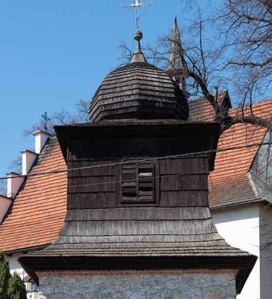 Zdjęcie nr 106: Kościół orientowany, murowany, jednonawowy z węższym prezbiterium zakończonym półkolistą absydą. Przy prezbiterium od północy znajduje się zakrystia, od południa kwadratowa kaplica św. Anny, a przy nawie od południa kruchta. Wnętrze kościoła nakryte jest nowym stropem, natomiast w kaplicy znajduje się sklepienie krzyżowo-żebrowe. Fasada zachodnia ujęta jest na narożnikach skośnymi szkarpami i zwieńczona schodkowym szczytem, podobnie zwieńczona jest kruchta południowa. Portal zachodni kamienny, z belkowaniem wspartym na dwóch liściastych konsolach ponad którymi edikula z płaskorzeźbionym krucyfiksem i klęczącymi postaciami męskimi. Na belkowaniu znajdują się dwa kartusze z herbami: po lewej herb Bończa, a nad nim litery „I” oraz „T”, a na prawo herb Szreniawa i litery „B” i „T”. Portal kruchty południowej jest również kamienny, podobny do zachodniego z inskrypcją: „IN LAVDEM ET GL[ORI]AM DEI O[MN]IP[OTENTIS] HO[NO]RE[M] / B(EATE) M(ARIAE) S(ANCTAE) V(IRGINIS) S(ANCTUS) AEGIDY ET OM(NIUM) SS. FIR. REGNÃTE [TERTIO] SIGISM[UN]DO / REGE POL[ONIAE] Z[?] HEMO[?] EP[ISCOP]O CRAC(OVIENSIS) BERN[AR]DO MACIEIOWSKI / NOVIT[ER] CAR[DINA]LI CRA[COVIENSE] DEI FACTO INTERI[M] PLEBA[N]O R[E]V[EREN]DO SEB(ASTIANO) / NAGRODIO A I SYRADIA PHI[LOSOPHI]AE DOCTORE COLLEG[I]A [MA]IORE / S. T(HEOLOGIAE) PVBLICO PROFES(SORE) PRAEP[OSI]TO S(ANCTA) AN(NAE) CRAC[OVIAE] DECIMARVM / ET FVNDI ECCL(ESIA)E HVIVS P[OST] IVRIS STREPITV(M) RESTITV / TORE ANNO OCTAVO PLEBANAT[U]S SVI. TEMPLVM HO(C) / [ dwa wiersze skute] DE' / NOWO AEDIFICATVM. ET. CONSTRVCTVM. ADIVTORIO / QVORVNDÃ ANNO D[OMINI] MDCIIII MENSE SEPTEMB[RE]”. Od południa świątyni umieszczone są trzy otwory okienne w kształcie stojących prostokątów, zamkniętych łukiem półkolistym, a w prezbiterium dwa małe okrągłe okna. Kościół nakryty jest dwoma dwuspadowymi dachami, nad prezbiterium nieco niższym, nad nawą zwieńczonym wąską i wysoką sygnaturką na dzwon. Wewnątrz świątyni na skrzyżowaniu nawy i prezbiterium umocowana jest drewniana belka tęczowa z ustawionym na niej krucyfiksem i figurami Matki Boskiej i św. Jana Ewangelisty. Chór zachodni drewniany, na planie prostokąta, pośrodku półkoliście zamknięty, wsparty na sześciu filarach, od północnego zachodu z obudowaną boazerią klatką schodową. 