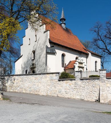 Zdjęcie nr 30: Kościół orientowany, murowany, jednonawowy z węższym prezbiterium zakończonym półkolistą absydą. Przy prezbiterium od północy znajduje się zakrystia, od południa kwadratowa kaplica św. Anny, a przy nawie od południa kruchta. Wnętrze kościoła nakryte jest nowym stropem, natomiast w kaplicy znajduje się sklepienie krzyżowo-żebrowe. Fasada zachodnia ujęta jest na narożnikach skośnymi szkarpami i zwieńczona schodkowym szczytem, podobnie zwieńczona jest kruchta południowa. Portal zachodni kamienny, z belkowaniem wspartym na dwóch liściastych konsolach ponad którymi edikula z płaskorzeźbionym krucyfiksem i klęczącymi postaciami męskimi. Na belkowaniu znajdują się dwa kartusze z herbami: po lewej herb Bończa, a nad nim litery „I” oraz „T”, a na prawo herb Szreniawa i litery „B” i „T”. Portal kruchty południowej jest również kamienny, podobny do zachodniego z inskrypcją: „IN LAVDEM ET GL[ORI]AM DEI O[MN]IP[OTENTIS] HO[NO]RE[M] / B(EATE) M(ARIAE) S(ANCTAE) V(IRGINIS) S(ANCTUS) AEGIDY ET OM(NIUM) SS. FIR. REGNÃTE [TERTIO] SIGISM[UN]DO / REGE POL[ONIAE] Z[?] HEMO[?] EP[ISCOP]O CRAC(OVIENSIS) BERN[AR]DO MACIEIOWSKI / NOVIT[ER] CAR[DINA]LI CRA[COVIENSE] DEI FACTO INTERI[M] PLEBA[N]O R[E]V[EREN]DO SEB(ASTIANO) / NAGRODIO A I SYRADIA PHI[LOSOPHI]AE DOCTORE COLLEG[I]A [MA]IORE / S. T(HEOLOGIAE) PVBLICO PROFES(SORE) PRAEP[OSI]TO S(ANCTA) AN(NAE) CRAC[OVIAE] DECIMARVM / ET FVNDI ECCL(ESIA)E HVIVS P[OST] IVRIS STREPITV(M) RESTITV / TORE ANNO OCTAVO PLEBANAT[U]S SVI. TEMPLVM HO(C) / [ dwa wiersze skute] DE' / NOWO AEDIFICATVM. ET. CONSTRVCTVM. ADIVTORIO / QVORVNDÃ ANNO D[OMINI] MDCIIII MENSE SEPTEMB[RE]”. Od południa świątyni umieszczone są trzy otwory okienne w kształcie stojących prostokątów, zamkniętych łukiem półkolistym, a w prezbiterium dwa małe okrągłe okna. Kościół nakryty jest dwoma dwuspadowymi dachami, nad prezbiterium nieco niższym, nad nawą zwieńczonym wąską i wysoką sygnaturką na dzwon. Wewnątrz świątyni na skrzyżowaniu nawy i prezbiterium umocowana jest drewniana belka tęczowa z ustawionym na niej krucyfiksem i figurami Matki Boskiej i św. Jana Ewangelisty. Chór zachodni drewniany, na planie prostokąta, pośrodku półkoliście zamknięty, wsparty na sześciu filarach, od północnego zachodu z obudowaną boazerią klatką schodową. 