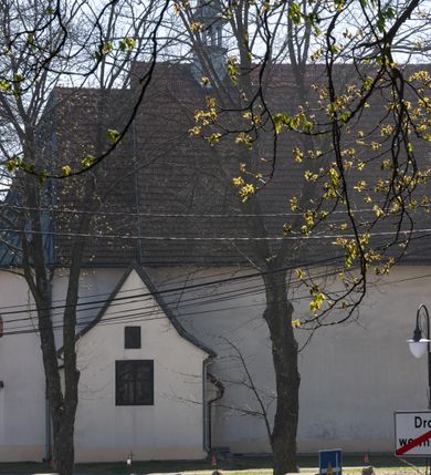 Zdjęcie nr 18: Kościół orientowany, murowany, jednonawowy z węższym prezbiterium zakończonym półkolistą absydą. Przy prezbiterium od północy znajduje się zakrystia, od południa kwadratowa kaplica św. Anny, a przy nawie od południa kruchta. Wnętrze kościoła nakryte jest nowym stropem, natomiast w kaplicy znajduje się sklepienie krzyżowo-żebrowe. Fasada zachodnia ujęta jest na narożnikach skośnymi szkarpami i zwieńczona schodkowym szczytem, podobnie zwieńczona jest kruchta południowa. Portal zachodni kamienny, z belkowaniem wspartym na dwóch liściastych konsolach ponad którymi edikula z płaskorzeźbionym krucyfiksem i klęczącymi postaciami męskimi. Na belkowaniu znajdują się dwa kartusze z herbami: po lewej herb Bończa, a nad nim litery „I” oraz „T”, a na prawo herb Szreniawa i litery „B” i „T”. Portal kruchty południowej jest również kamienny, podobny do zachodniego z inskrypcją: „IN LAVDEM ET GL[ORI]AM DEI O[MN]IP[OTENTIS] HO[NO]RE[M] / B(EATE) M(ARIAE) S(ANCTAE) V(IRGINIS) S(ANCTUS) AEGIDY ET OM(NIUM) SS. FIR. REGNÃTE [TERTIO] SIGISM[UN]DO / REGE POL[ONIAE] Z[?] HEMO[?] EP[ISCOP]O CRAC(OVIENSIS) BERN[AR]DO MACIEIOWSKI / NOVIT[ER] CAR[DINA]LI CRA[COVIENSE] DEI FACTO INTERI[M] PLEBA[N]O R[E]V[EREN]DO SEB(ASTIANO) / NAGRODIO A I SYRADIA PHI[LOSOPHI]AE DOCTORE COLLEG[I]A [MA]IORE / S. T(HEOLOGIAE) PVBLICO PROFES(SORE) PRAEP[OSI]TO S(ANCTA) AN(NAE) CRAC[OVIAE] DECIMARVM / ET FVNDI ECCL(ESIA)E HVIVS P[OST] IVRIS STREPITV(M) RESTITV / TORE ANNO OCTAVO PLEBANAT[U]S SVI. TEMPLVM HO(C) / [ dwa wiersze skute] DE&#039; / NOWO AEDIFICATVM. ET. CONSTRVCTVM. ADIVTORIO / QVORVNDÃ ANNO D[OMINI] MDCIIII MENSE SEPTEMB[RE]”. Od południa świątyni umieszczone są trzy otwory okienne w kształcie stojących prostokątów, zamkniętych łukiem półkolistym, a w prezbiterium dwa małe okrągłe okna. Kościół nakryty jest dwoma dwuspadowymi dachami, nad prezbiterium nieco niższym, nad nawą zwieńczonym wąską i wysoką sygnaturką na dzwon. Wewnątrz świątyni na skrzyżowaniu nawy i prezbiterium umocowana jest drewniana belka tęczowa z ustawionym na niej krucyfiksem i figurami Matki Boskiej i św. Jana Ewangelisty. Chór zachodni drewniany, na planie prostokąta, pośrodku półkoliście zamknięty, wsparty na sześciu filarach, od północnego zachodu z obudowaną boazerią klatką schodową. 