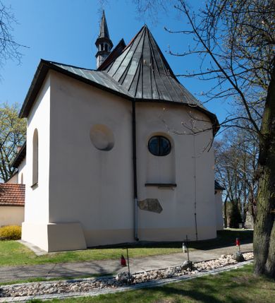 Zdjęcie nr 27: Kościół orientowany, murowany, jednonawowy z węższym prezbiterium zakończonym półkolistą absydą. Przy prezbiterium od północy znajduje się zakrystia, od południa kwadratowa kaplica św. Anny, a przy nawie od południa kruchta. Wnętrze kościoła nakryte jest nowym stropem, natomiast w kaplicy znajduje się sklepienie krzyżowo-żebrowe. Fasada zachodnia ujęta jest na narożnikach skośnymi szkarpami i zwieńczona schodkowym szczytem, podobnie zwieńczona jest kruchta południowa. Portal zachodni kamienny, z belkowaniem wspartym na dwóch liściastych konsolach ponad którymi edikula z płaskorzeźbionym krucyfiksem i klęczącymi postaciami męskimi. Na belkowaniu znajdują się dwa kartusze z herbami: po lewej herb Bończa, a nad nim litery „I” oraz „T”, a na prawo herb Szreniawa i litery „B” i „T”. Portal kruchty południowej jest również kamienny, podobny do zachodniego z inskrypcją: „IN LAVDEM ET GL[ORI]AM DEI O[MN]IP[OTENTIS] HO[NO]RE[M] / B(EATE) M(ARIAE) S(ANCTAE) V(IRGINIS) S(ANCTUS) AEGIDY ET OM(NIUM) SS. FIR. REGNÃTE [TERTIO] SIGISM[UN]DO / REGE POL[ONIAE] Z[?] HEMO[?] EP[ISCOP]O CRAC(OVIENSIS) BERN[AR]DO MACIEIOWSKI / NOVIT[ER] CAR[DINA]LI CRA[COVIENSE] DEI FACTO INTERI[M] PLEBA[N]O R[E]V[EREN]DO SEB(ASTIANO) / NAGRODIO A I SYRADIA PHI[LOSOPHI]AE DOCTORE COLLEG[I]A [MA]IORE / S. T(HEOLOGIAE) PVBLICO PROFES(SORE) PRAEP[OSI]TO S(ANCTA) AN(NAE) CRAC[OVIAE] DECIMARVM / ET FVNDI ECCL(ESIA)E HVIVS P[OST] IVRIS STREPITV(M) RESTITV / TORE ANNO OCTAVO PLEBANAT[U]S SVI. TEMPLVM HO(C) / [ dwa wiersze skute] DE&#039; / NOWO AEDIFICATVM. ET. CONSTRVCTVM. ADIVTORIO / QVORVNDÃ ANNO D[OMINI] MDCIIII MENSE SEPTEMB[RE]”. Od południa świątyni umieszczone są trzy otwory okienne w kształcie stojących prostokątów, zamkniętych łukiem półkolistym, a w prezbiterium dwa małe okrągłe okna. Kościół nakryty jest dwoma dwuspadowymi dachami, nad prezbiterium nieco niższym, nad nawą zwieńczonym wąską i wysoką sygnaturką na dzwon. Wewnątrz świątyni na skrzyżowaniu nawy i prezbiterium umocowana jest drewniana belka tęczowa z ustawionym na niej krucyfiksem i figurami Matki Boskiej i św. Jana Ewangelisty. Chór zachodni drewniany, na planie prostokąta, pośrodku półkoliście zamknięty, wsparty na sześciu filarach, od północnego zachodu z obudowaną boazerią klatką schodową. 