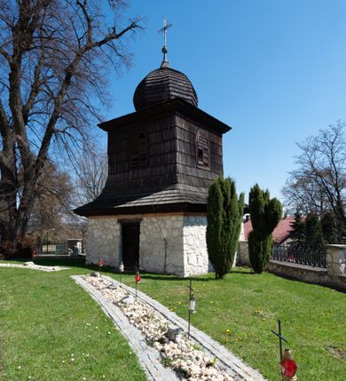 Zdjęcie nr 102: Kościół orientowany, murowany, jednonawowy z węższym prezbiterium zakończonym półkolistą absydą. Przy prezbiterium od północy znajduje się zakrystia, od południa kwadratowa kaplica św. Anny, a przy nawie od południa kruchta. Wnętrze kościoła nakryte jest nowym stropem, natomiast w kaplicy znajduje się sklepienie krzyżowo-żebrowe. Fasada zachodnia ujęta jest na narożnikach skośnymi szkarpami i zwieńczona schodkowym szczytem, podobnie zwieńczona jest kruchta południowa. Portal zachodni kamienny, z belkowaniem wspartym na dwóch liściastych konsolach ponad którymi edikula z płaskorzeźbionym krucyfiksem i klęczącymi postaciami męskimi. Na belkowaniu znajdują się dwa kartusze z herbami: po lewej herb Bończa, a nad nim litery „I” oraz „T”, a na prawo herb Szreniawa i litery „B” i „T”. Portal kruchty południowej jest również kamienny, podobny do zachodniego z inskrypcją: „IN LAVDEM ET GL[ORI]AM DEI O[MN]IP[OTENTIS] HO[NO]RE[M] / B(EATE) M(ARIAE) S(ANCTAE) V(IRGINIS) S(ANCTUS) AEGIDY ET OM(NIUM) SS. FIR. REGNÃTE [TERTIO] SIGISM[UN]DO / REGE POL[ONIAE] Z[?] HEMO[?] EP[ISCOP]O CRAC(OVIENSIS) BERN[AR]DO MACIEIOWSKI / NOVIT[ER] CAR[DINA]LI CRA[COVIENSE] DEI FACTO INTERI[M] PLEBA[N]O R[E]V[EREN]DO SEB(ASTIANO) / NAGRODIO A I SYRADIA PHI[LOSOPHI]AE DOCTORE COLLEG[I]A [MA]IORE / S. T(HEOLOGIAE) PVBLICO PROFES(SORE) PRAEP[OSI]TO S(ANCTA) AN(NAE) CRAC[OVIAE] DECIMARVM / ET FVNDI ECCL(ESIA)E HVIVS P[OST] IVRIS STREPITV(M) RESTITV / TORE ANNO OCTAVO PLEBANAT[U]S SVI. TEMPLVM HO(C) / [ dwa wiersze skute] DE' / NOWO AEDIFICATVM. ET. CONSTRVCTVM. ADIVTORIO / QVORVNDÃ ANNO D[OMINI] MDCIIII MENSE SEPTEMB[RE]”. Od południa świątyni umieszczone są trzy otwory okienne w kształcie stojących prostokątów, zamkniętych łukiem półkolistym, a w prezbiterium dwa małe okrągłe okna. Kościół nakryty jest dwoma dwuspadowymi dachami, nad prezbiterium nieco niższym, nad nawą zwieńczonym wąską i wysoką sygnaturką na dzwon. Wewnątrz świątyni na skrzyżowaniu nawy i prezbiterium umocowana jest drewniana belka tęczowa z ustawionym na niej krucyfiksem i figurami Matki Boskiej i św. Jana Ewangelisty. Chór zachodni drewniany, na planie prostokąta, pośrodku półkoliście zamknięty, wsparty na sześciu filarach, od północnego zachodu z obudowaną boazerią klatką schodową. 