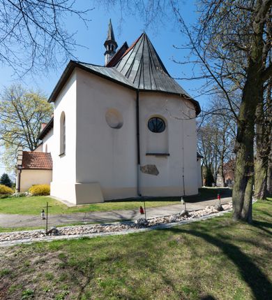 Zdjęcie nr 26: Kościół orientowany, murowany, jednonawowy z węższym prezbiterium zakończonym półkolistą absydą. Przy prezbiterium od północy znajduje się zakrystia, od południa kwadratowa kaplica św. Anny, a przy nawie od południa kruchta. Wnętrze kościoła nakryte jest nowym stropem, natomiast w kaplicy znajduje się sklepienie krzyżowo-żebrowe. Fasada zachodnia ujęta jest na narożnikach skośnymi szkarpami i zwieńczona schodkowym szczytem, podobnie zwieńczona jest kruchta południowa. Portal zachodni kamienny, z belkowaniem wspartym na dwóch liściastych konsolach ponad którymi edikula z płaskorzeźbionym krucyfiksem i klęczącymi postaciami męskimi. Na belkowaniu znajdują się dwa kartusze z herbami: po lewej herb Bończa, a nad nim litery „I” oraz „T”, a na prawo herb Szreniawa i litery „B” i „T”. Portal kruchty południowej jest również kamienny, podobny do zachodniego z inskrypcją: „IN LAVDEM ET GL[ORI]AM DEI O[MN]IP[OTENTIS] HO[NO]RE[M] / B(EATE) M(ARIAE) S(ANCTAE) V(IRGINIS) S(ANCTUS) AEGIDY ET OM(NIUM) SS. FIR. REGNÃTE [TERTIO] SIGISM[UN]DO / REGE POL[ONIAE] Z[?] HEMO[?] EP[ISCOP]O CRAC(OVIENSIS) BERN[AR]DO MACIEIOWSKI / NOVIT[ER] CAR[DINA]LI CRA[COVIENSE] DEI FACTO INTERI[M] PLEBA[N]O R[E]V[EREN]DO SEB(ASTIANO) / NAGRODIO A I SYRADIA PHI[LOSOPHI]AE DOCTORE COLLEG[I]A [MA]IORE / S. T(HEOLOGIAE) PVBLICO PROFES(SORE) PRAEP[OSI]TO S(ANCTA) AN(NAE) CRAC[OVIAE] DECIMARVM / ET FVNDI ECCL(ESIA)E HVIVS P[OST] IVRIS STREPITV(M) RESTITV / TORE ANNO OCTAVO PLEBANAT[U]S SVI. TEMPLVM HO(C) / [ dwa wiersze skute] DE' / NOWO AEDIFICATVM. ET. CONSTRVCTVM. ADIVTORIO / QVORVNDÃ ANNO D[OMINI] MDCIIII MENSE SEPTEMB[RE]”. Od południa świątyni umieszczone są trzy otwory okienne w kształcie stojących prostokątów, zamkniętych łukiem półkolistym, a w prezbiterium dwa małe okrągłe okna. Kościół nakryty jest dwoma dwuspadowymi dachami, nad prezbiterium nieco niższym, nad nawą zwieńczonym wąską i wysoką sygnaturką na dzwon. Wewnątrz świątyni na skrzyżowaniu nawy i prezbiterium umocowana jest drewniana belka tęczowa z ustawionym na niej krucyfiksem i figurami Matki Boskiej i św. Jana Ewangelisty. Chór zachodni drewniany, na planie prostokąta, pośrodku półkoliście zamknięty, wsparty na sześciu filarach, od północnego zachodu z obudowaną boazerią klatką schodową. 