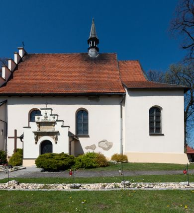 Zdjęcie nr 74: Kościół orientowany, murowany, jednonawowy z węższym prezbiterium zakończonym półkolistą absydą. Przy prezbiterium od północy znajduje się zakrystia, od południa kwadratowa kaplica św. Anny, a przy nawie od południa kruchta. Wnętrze kościoła nakryte jest nowym stropem, natomiast w kaplicy znajduje się sklepienie krzyżowo-żebrowe. Fasada zachodnia ujęta jest na narożnikach skośnymi szkarpami i zwieńczona schodkowym szczytem, podobnie zwieńczona jest kruchta południowa. Portal zachodni kamienny, z belkowaniem wspartym na dwóch liściastych konsolach ponad którymi edikula z płaskorzeźbionym krucyfiksem i klęczącymi postaciami męskimi. Na belkowaniu znajdują się dwa kartusze z herbami: po lewej herb Bończa, a nad nim litery „I” oraz „T”, a na prawo herb Szreniawa i litery „B” i „T”. Portal kruchty południowej jest również kamienny, podobny do zachodniego z inskrypcją: „IN LAVDEM ET GL[ORI]AM DEI O[MN]IP[OTENTIS] HO[NO]RE[M] / B(EATE) M(ARIAE) S(ANCTAE) V(IRGINIS) S(ANCTUS) AEGIDY ET OM(NIUM) SS. FIR. REGNÃTE [TERTIO] SIGISM[UN]DO / REGE POL[ONIAE] Z[?] HEMO[?] EP[ISCOP]O CRAC(OVIENSIS) BERN[AR]DO MACIEIOWSKI / NOVIT[ER] CAR[DINA]LI CRA[COVIENSE] DEI FACTO INTERI[M] PLEBA[N]O R[E]V[EREN]DO SEB(ASTIANO) / NAGRODIO A I SYRADIA PHI[LOSOPHI]AE DOCTORE COLLEG[I]A [MA]IORE / S. T(HEOLOGIAE) PVBLICO PROFES(SORE) PRAEP[OSI]TO S(ANCTA) AN(NAE) CRAC[OVIAE] DECIMARVM / ET FVNDI ECCL(ESIA)E HVIVS P[OST] IVRIS STREPITV(M) RESTITV / TORE ANNO OCTAVO PLEBANAT[U]S SVI. TEMPLVM HO(C) / [ dwa wiersze skute] DE&#039; / NOWO AEDIFICATVM. ET. CONSTRVCTVM. ADIVTORIO / QVORVNDÃ ANNO D[OMINI] MDCIIII MENSE SEPTEMB[RE]”. Od południa świątyni umieszczone są trzy otwory okienne w kształcie stojących prostokątów, zamkniętych łukiem półkolistym, a w prezbiterium dwa małe okrągłe okna. Kościół nakryty jest dwoma dwuspadowymi dachami, nad prezbiterium nieco niższym, nad nawą zwieńczonym wąską i wysoką sygnaturką na dzwon. Wewnątrz świątyni na skrzyżowaniu nawy i prezbiterium umocowana jest drewniana belka tęczowa z ustawionym na niej krucyfiksem i figurami Matki Boskiej i św. Jana Ewangelisty. Chór zachodni drewniany, na planie prostokąta, pośrodku półkoliście zamknięty, wsparty na sześciu filarach, od północnego zachodu z obudowaną boazerią klatką schodową. 