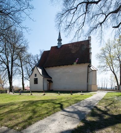 Zdjęcie nr 16: Kościół orientowany, murowany, jednonawowy z węższym prezbiterium zakończonym półkolistą absydą. Przy prezbiterium od północy znajduje się zakrystia, od południa kwadratowa kaplica św. Anny, a przy nawie od południa kruchta. Wnętrze kościoła nakryte jest nowym stropem, natomiast w kaplicy znajduje się sklepienie krzyżowo-żebrowe. Fasada zachodnia ujęta jest na narożnikach skośnymi szkarpami i zwieńczona schodkowym szczytem, podobnie zwieńczona jest kruchta południowa. Portal zachodni kamienny, z belkowaniem wspartym na dwóch liściastych konsolach ponad którymi edikula z płaskorzeźbionym krucyfiksem i klęczącymi postaciami męskimi. Na belkowaniu znajdują się dwa kartusze z herbami: po lewej herb Bończa, a nad nim litery „I” oraz „T”, a na prawo herb Szreniawa i litery „B” i „T”. Portal kruchty południowej jest również kamienny, podobny do zachodniego z inskrypcją: „IN LAVDEM ET GL[ORI]AM DEI O[MN]IP[OTENTIS] HO[NO]RE[M] / B(EATE) M(ARIAE) S(ANCTAE) V(IRGINIS) S(ANCTUS) AEGIDY ET OM(NIUM) SS. FIR. REGNÃTE [TERTIO] SIGISM[UN]DO / REGE POL[ONIAE] Z[?] HEMO[?] EP[ISCOP]O CRAC(OVIENSIS) BERN[AR]DO MACIEIOWSKI / NOVIT[ER] CAR[DINA]LI CRA[COVIENSE] DEI FACTO INTERI[M] PLEBA[N]O R[E]V[EREN]DO SEB(ASTIANO) / NAGRODIO A I SYRADIA PHI[LOSOPHI]AE DOCTORE COLLEG[I]A [MA]IORE / S. T(HEOLOGIAE) PVBLICO PROFES(SORE) PRAEP[OSI]TO S(ANCTA) AN(NAE) CRAC[OVIAE] DECIMARVM / ET FVNDI ECCL(ESIA)E HVIVS P[OST] IVRIS STREPITV(M) RESTITV / TORE ANNO OCTAVO PLEBANAT[U]S SVI. TEMPLVM HO(C) / [ dwa wiersze skute] DE' / NOWO AEDIFICATVM. ET. CONSTRVCTVM. ADIVTORIO / QVORVNDÃ ANNO D[OMINI] MDCIIII MENSE SEPTEMB[RE]”. Od południa świątyni umieszczone są trzy otwory okienne w kształcie stojących prostokątów, zamkniętych łukiem półkolistym, a w prezbiterium dwa małe okrągłe okna. Kościół nakryty jest dwoma dwuspadowymi dachami, nad prezbiterium nieco niższym, nad nawą zwieńczonym wąską i wysoką sygnaturką na dzwon. Wewnątrz świątyni na skrzyżowaniu nawy i prezbiterium umocowana jest drewniana belka tęczowa z ustawionym na niej krucyfiksem i figurami Matki Boskiej i św. Jana Ewangelisty. Chór zachodni drewniany, na planie prostokąta, pośrodku półkoliście zamknięty, wsparty na sześciu filarach, od północnego zachodu z obudowaną boazerią klatką schodową. 