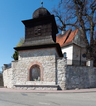 Zdjęcie nr 97: Kościół orientowany, murowany, jednonawowy z węższym prezbiterium zakończonym półkolistą absydą. Przy prezbiterium od północy znajduje się zakrystia, od południa kwadratowa kaplica św. Anny, a przy nawie od południa kruchta. Wnętrze kościoła nakryte jest nowym stropem, natomiast w kaplicy znajduje się sklepienie krzyżowo-żebrowe. Fasada zachodnia ujęta jest na narożnikach skośnymi szkarpami i zwieńczona schodkowym szczytem, podobnie zwieńczona jest kruchta południowa. Portal zachodni kamienny, z belkowaniem wspartym na dwóch liściastych konsolach ponad którymi edikula z płaskorzeźbionym krucyfiksem i klęczącymi postaciami męskimi. Na belkowaniu znajdują się dwa kartusze z herbami: po lewej herb Bończa, a nad nim litery „I” oraz „T”, a na prawo herb Szreniawa i litery „B” i „T”. Portal kruchty południowej jest również kamienny, podobny do zachodniego z inskrypcją: „IN LAVDEM ET GL[ORI]AM DEI O[MN]IP[OTENTIS] HO[NO]RE[M] / B(EATE) M(ARIAE) S(ANCTAE) V(IRGINIS) S(ANCTUS) AEGIDY ET OM(NIUM) SS. FIR. REGNÃTE [TERTIO] SIGISM[UN]DO / REGE POL[ONIAE] Z[?] HEMO[?] EP[ISCOP]O CRAC(OVIENSIS) BERN[AR]DO MACIEIOWSKI / NOVIT[ER] CAR[DINA]LI CRA[COVIENSE] DEI FACTO INTERI[M] PLEBA[N]O R[E]V[EREN]DO SEB(ASTIANO) / NAGRODIO A I SYRADIA PHI[LOSOPHI]AE DOCTORE COLLEG[I]A [MA]IORE / S. T(HEOLOGIAE) PVBLICO PROFES(SORE) PRAEP[OSI]TO S(ANCTA) AN(NAE) CRAC[OVIAE] DECIMARVM / ET FVNDI ECCL(ESIA)E HVIVS P[OST] IVRIS STREPITV(M) RESTITV / TORE ANNO OCTAVO PLEBANAT[U]S SVI. TEMPLVM HO(C) / [ dwa wiersze skute] DE' / NOWO AEDIFICATVM. ET. CONSTRVCTVM. ADIVTORIO / QVORVNDÃ ANNO D[OMINI] MDCIIII MENSE SEPTEMB[RE]”. Od południa świątyni umieszczone są trzy otwory okienne w kształcie stojących prostokątów, zamkniętych łukiem półkolistym, a w prezbiterium dwa małe okrągłe okna. Kościół nakryty jest dwoma dwuspadowymi dachami, nad prezbiterium nieco niższym, nad nawą zwieńczonym wąską i wysoką sygnaturką na dzwon. Wewnątrz świątyni na skrzyżowaniu nawy i prezbiterium umocowana jest drewniana belka tęczowa z ustawionym na niej krucyfiksem i figurami Matki Boskiej i św. Jana Ewangelisty. Chór zachodni drewniany, na planie prostokąta, pośrodku półkoliście zamknięty, wsparty na sześciu filarach, od północnego zachodu z obudowaną boazerią klatką schodową. 