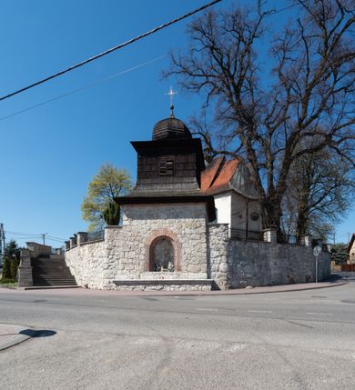 Zdjęcie nr 92: Kościół orientowany, murowany, jednonawowy z węższym prezbiterium zakończonym półkolistą absydą. Przy prezbiterium od północy znajduje się zakrystia, od południa kwadratowa kaplica św. Anny, a przy nawie od południa kruchta. Wnętrze kościoła nakryte jest nowym stropem, natomiast w kaplicy znajduje się sklepienie krzyżowo-żebrowe. Fasada zachodnia ujęta jest na narożnikach skośnymi szkarpami i zwieńczona schodkowym szczytem, podobnie zwieńczona jest kruchta południowa. Portal zachodni kamienny, z belkowaniem wspartym na dwóch liściastych konsolach ponad którymi edikula z płaskorzeźbionym krucyfiksem i klęczącymi postaciami męskimi. Na belkowaniu znajdują się dwa kartusze z herbami: po lewej herb Bończa, a nad nim litery „I” oraz „T”, a na prawo herb Szreniawa i litery „B” i „T”. Portal kruchty południowej jest również kamienny, podobny do zachodniego z inskrypcją: „IN LAVDEM ET GL[ORI]AM DEI O[MN]IP[OTENTIS] HO[NO]RE[M] / B(EATE) M(ARIAE) S(ANCTAE) V(IRGINIS) S(ANCTUS) AEGIDY ET OM(NIUM) SS. FIR. REGNÃTE [TERTIO] SIGISM[UN]DO / REGE POL[ONIAE] Z[?] HEMO[?] EP[ISCOP]O CRAC(OVIENSIS) BERN[AR]DO MACIEIOWSKI / NOVIT[ER] CAR[DINA]LI CRA[COVIENSE] DEI FACTO INTERI[M] PLEBA[N]O R[E]V[EREN]DO SEB(ASTIANO) / NAGRODIO A I SYRADIA PHI[LOSOPHI]AE DOCTORE COLLEG[I]A [MA]IORE / S. T(HEOLOGIAE) PVBLICO PROFES(SORE) PRAEP[OSI]TO S(ANCTA) AN(NAE) CRAC[OVIAE] DECIMARVM / ET FVNDI ECCL(ESIA)E HVIVS P[OST] IVRIS STREPITV(M) RESTITV / TORE ANNO OCTAVO PLEBANAT[U]S SVI. TEMPLVM HO(C) / [ dwa wiersze skute] DE' / NOWO AEDIFICATVM. ET. CONSTRVCTVM. ADIVTORIO / QVORVNDÃ ANNO D[OMINI] MDCIIII MENSE SEPTEMB[RE]”. Od południa świątyni umieszczone są trzy otwory okienne w kształcie stojących prostokątów, zamkniętych łukiem półkolistym, a w prezbiterium dwa małe okrągłe okna. Kościół nakryty jest dwoma dwuspadowymi dachami, nad prezbiterium nieco niższym, nad nawą zwieńczonym wąską i wysoką sygnaturką na dzwon. Wewnątrz świątyni na skrzyżowaniu nawy i prezbiterium umocowana jest drewniana belka tęczowa z ustawionym na niej krucyfiksem i figurami Matki Boskiej i św. Jana Ewangelisty. Chór zachodni drewniany, na planie prostokąta, pośrodku półkoliście zamknięty, wsparty na sześciu filarach, od północnego zachodu z obudowaną boazerią klatką schodową. 