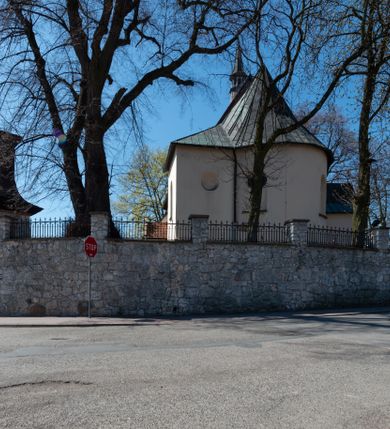 Zdjęcie nr 23: Kościół orientowany, murowany, jednonawowy z węższym prezbiterium zakończonym półkolistą absydą. Przy prezbiterium od północy znajduje się zakrystia, od południa kwadratowa kaplica św. Anny, a przy nawie od południa kruchta. Wnętrze kościoła nakryte jest nowym stropem, natomiast w kaplicy znajduje się sklepienie krzyżowo-żebrowe. Fasada zachodnia ujęta jest na narożnikach skośnymi szkarpami i zwieńczona schodkowym szczytem, podobnie zwieńczona jest kruchta południowa. Portal zachodni kamienny, z belkowaniem wspartym na dwóch liściastych konsolach ponad którymi edikula z płaskorzeźbionym krucyfiksem i klęczącymi postaciami męskimi. Na belkowaniu znajdują się dwa kartusze z herbami: po lewej herb Bończa, a nad nim litery „I” oraz „T”, a na prawo herb Szreniawa i litery „B” i „T”. Portal kruchty południowej jest również kamienny, podobny do zachodniego z inskrypcją: „IN LAVDEM ET GL[ORI]AM DEI O[MN]IP[OTENTIS] HO[NO]RE[M] / B(EATE) M(ARIAE) S(ANCTAE) V(IRGINIS) S(ANCTUS) AEGIDY ET OM(NIUM) SS. FIR. REGNÃTE [TERTIO] SIGISM[UN]DO / REGE POL[ONIAE] Z[?] HEMO[?] EP[ISCOP]O CRAC(OVIENSIS) BERN[AR]DO MACIEIOWSKI / NOVIT[ER] CAR[DINA]LI CRA[COVIENSE] DEI FACTO INTERI[M] PLEBA[N]O R[E]V[EREN]DO SEB(ASTIANO) / NAGRODIO A I SYRADIA PHI[LOSOPHI]AE DOCTORE COLLEG[I]A [MA]IORE / S. T(HEOLOGIAE) PVBLICO PROFES(SORE) PRAEP[OSI]TO S(ANCTA) AN(NAE) CRAC[OVIAE] DECIMARVM / ET FVNDI ECCL(ESIA)E HVIVS P[OST] IVRIS STREPITV(M) RESTITV / TORE ANNO OCTAVO PLEBANAT[U]S SVI. TEMPLVM HO(C) / [ dwa wiersze skute] DE&#039; / NOWO AEDIFICATVM. ET. CONSTRVCTVM. ADIVTORIO / QVORVNDÃ ANNO D[OMINI] MDCIIII MENSE SEPTEMB[RE]”. Od południa świątyni umieszczone są trzy otwory okienne w kształcie stojących prostokątów, zamkniętych łukiem półkolistym, a w prezbiterium dwa małe okrągłe okna. Kościół nakryty jest dwoma dwuspadowymi dachami, nad prezbiterium nieco niższym, nad nawą zwieńczonym wąską i wysoką sygnaturką na dzwon. Wewnątrz świątyni na skrzyżowaniu nawy i prezbiterium umocowana jest drewniana belka tęczowa z ustawionym na niej krucyfiksem i figurami Matki Boskiej i św. Jana Ewangelisty. Chór zachodni drewniany, na planie prostokąta, pośrodku półkoliście zamknięty, wsparty na sześciu filarach, od północnego zachodu z obudowaną boazerią klatką schodową. 