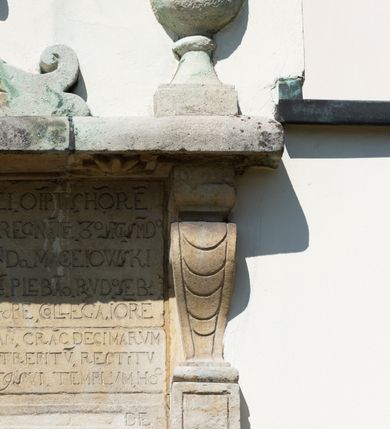 Zdjęcie nr 56: Kościół orientowany, murowany, jednonawowy z węższym prezbiterium zakończonym półkolistą absydą. Przy prezbiterium od północy znajduje się zakrystia, od południa kwadratowa kaplica św. Anny, a przy nawie od południa kruchta. Wnętrze kościoła nakryte jest nowym stropem, natomiast w kaplicy znajduje się sklepienie krzyżowo-żebrowe. Fasada zachodnia ujęta jest na narożnikach skośnymi szkarpami i zwieńczona schodkowym szczytem, podobnie zwieńczona jest kruchta południowa. Portal zachodni kamienny, z belkowaniem wspartym na dwóch liściastych konsolach ponad którymi edikula z płaskorzeźbionym krucyfiksem i klęczącymi postaciami męskimi. Na belkowaniu znajdują się dwa kartusze z herbami: po lewej herb Bończa, a nad nim litery „I” oraz „T”, a na prawo herb Szreniawa i litery „B” i „T”. Portal kruchty południowej jest również kamienny, podobny do zachodniego z inskrypcją: „IN LAVDEM ET GL[ORI]AM DEI O[MN]IP[OTENTIS] HO[NO]RE[M] / B(EATE) M(ARIAE) S(ANCTAE) V(IRGINIS) S(ANCTUS) AEGIDY ET OM(NIUM) SS. FIR. REGNÃTE [TERTIO] SIGISM[UN]DO / REGE POL[ONIAE] Z[?] HEMO[?] EP[ISCOP]O CRAC(OVIENSIS) BERN[AR]DO MACIEIOWSKI / NOVIT[ER] CAR[DINA]LI CRA[COVIENSE] DEI FACTO INTERI[M] PLEBA[N]O R[E]V[EREN]DO SEB(ASTIANO) / NAGRODIO A I SYRADIA PHI[LOSOPHI]AE DOCTORE COLLEG[I]A [MA]IORE / S. T(HEOLOGIAE) PVBLICO PROFES(SORE) PRAEP[OSI]TO S(ANCTA) AN(NAE) CRAC[OVIAE] DECIMARVM / ET FVNDI ECCL(ESIA)E HVIVS P[OST] IVRIS STREPITV(M) RESTITV / TORE ANNO OCTAVO PLEBANAT[U]S SVI. TEMPLVM HO(C) / [ dwa wiersze skute] DE&#039; / NOWO AEDIFICATVM. ET. CONSTRVCTVM. ADIVTORIO / QVORVNDÃ ANNO D[OMINI] MDCIIII MENSE SEPTEMB[RE]”. Od południa świątyni umieszczone są trzy otwory okienne w kształcie stojących prostokątów, zamkniętych łukiem półkolistym, a w prezbiterium dwa małe okrągłe okna. Kościół nakryty jest dwoma dwuspadowymi dachami, nad prezbiterium nieco niższym, nad nawą zwieńczonym wąską i wysoką sygnaturką na dzwon. Wewnątrz świątyni na skrzyżowaniu nawy i prezbiterium umocowana jest drewniana belka tęczowa z ustawionym na niej krucyfiksem i figurami Matki Boskiej i św. Jana Ewangelisty. Chór zachodni drewniany, na planie prostokąta, pośrodku półkoliście zamknięty, wsparty na sześciu filarach, od północnego zachodu z obudowaną boazerią klatką schodową. 