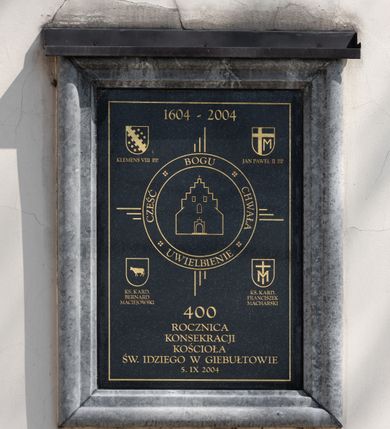 Zdjęcie nr 61: Kościół orientowany, murowany, jednonawowy z węższym prezbiterium zakończonym półkolistą absydą. Przy prezbiterium od północy znajduje się zakrystia, od południa kwadratowa kaplica św. Anny, a przy nawie od południa kruchta. Wnętrze kościoła nakryte jest nowym stropem, natomiast w kaplicy znajduje się sklepienie krzyżowo-żebrowe. Fasada zachodnia ujęta jest na narożnikach skośnymi szkarpami i zwieńczona schodkowym szczytem, podobnie zwieńczona jest kruchta południowa. Portal zachodni kamienny, z belkowaniem wspartym na dwóch liściastych konsolach ponad którymi edikula z płaskorzeźbionym krucyfiksem i klęczącymi postaciami męskimi. Na belkowaniu znajdują się dwa kartusze z herbami: po lewej herb Bończa, a nad nim litery „I” oraz „T”, a na prawo herb Szreniawa i litery „B” i „T”. Portal kruchty południowej jest również kamienny, podobny do zachodniego z inskrypcją: „IN LAVDEM ET GL[ORI]AM DEI O[MN]IP[OTENTIS] HO[NO]RE[M] / B(EATE) M(ARIAE) S(ANCTAE) V(IRGINIS) S(ANCTUS) AEGIDY ET OM(NIUM) SS. FIR. REGNÃTE [TERTIO] SIGISM[UN]DO / REGE POL[ONIAE] Z[?] HEMO[?] EP[ISCOP]O CRAC(OVIENSIS) BERN[AR]DO MACIEIOWSKI / NOVIT[ER] CAR[DINA]LI CRA[COVIENSE] DEI FACTO INTERI[M] PLEBA[N]O R[E]V[EREN]DO SEB(ASTIANO) / NAGRODIO A I SYRADIA PHI[LOSOPHI]AE DOCTORE COLLEG[I]A [MA]IORE / S. T(HEOLOGIAE) PVBLICO PROFES(SORE) PRAEP[OSI]TO S(ANCTA) AN(NAE) CRAC[OVIAE] DECIMARVM / ET FVNDI ECCL(ESIA)E HVIVS P[OST] IVRIS STREPITV(M) RESTITV / TORE ANNO OCTAVO PLEBANAT[U]S SVI. TEMPLVM HO(C) / [ dwa wiersze skute] DE' / NOWO AEDIFICATVM. ET. CONSTRVCTVM. ADIVTORIO / QVORVNDÃ ANNO D[OMINI] MDCIIII MENSE SEPTEMB[RE]”. Od południa świątyni umieszczone są trzy otwory okienne w kształcie stojących prostokątów, zamkniętych łukiem półkolistym, a w prezbiterium dwa małe okrągłe okna. Kościół nakryty jest dwoma dwuspadowymi dachami, nad prezbiterium nieco niższym, nad nawą zwieńczonym wąską i wysoką sygnaturką na dzwon. Wewnątrz świątyni na skrzyżowaniu nawy i prezbiterium umocowana jest drewniana belka tęczowa z ustawionym na niej krucyfiksem i figurami Matki Boskiej i św. Jana Ewangelisty. Chór zachodni drewniany, na planie prostokąta, pośrodku półkoliście zamknięty, wsparty na sześciu filarach, od północnego zachodu z obudowaną boazerią klatką schodową. 