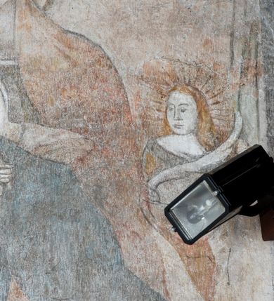 Zdjęcie nr 4: Na ścianie północnej prezbiterium w pierwszej kwaterze od lewej strony została ukazana św. Barbara z mieczem w lewej dłoni i palmą męczeństwa w prawej. W kolejnej kwaterze freski nie zachowały się w całości. W górnej części podwieszone są drapowane tkaniny, po lewej stronie widać dwie uskrzydlone główki aniołków, a po prawej stronie postać nierozpoznanej świętej męczennicy z palmą męczeństwa i księgą w dłoniach. Na ścianie południowej prezbiterium po prawej stronie jest przedstawienie św. Zofii z córkami ujęte w kwaterę w kształcie leżącego prostokąta. Pośrodku znajduje się św. Zofia z rękami złożonymi do modlitwy, na głowie ma zamkniętą koronę, po jej prawie stronie stoją dwie córki, a po lewej trzecia córka. Wszystkie córki zostały ukazane z palmami męczeństwa w dłoniach. Pozostałą powierzchnię ściany wypełniają dekoracje ornamentalne, uskrzydlone anioły, a w dolnej partii zacheuszki. Łuk arkady zdobią arma Christi, które otwierają kolejny cykl przedstawień w kaplicy św. Anny. Prezbiterium obiega od góry szeroki fryz z podwieszoną draperią, pomiędzy którą ukazane są winne grona.