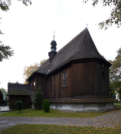 Zdjęcie nr 22: Kościół orientowany, pierwotnie na rzucie krzyża łacińskiego, jednonawowy, z kaplicami bocznymi od północy i południa, z prezbiterium prostokątnym zamkniętym wielobocznie. Obecnie w miejscu drewnianej kaplicy północnej murowana kaplica grobowa, a przy prezbiterium murowana prostokątna zakrystia i skarbczyk (1622 r.); nawa przedłużona ku zachodowi (1878-1879). Przy zachodniej części nawy, od południa, prostokątna drewniana kruchta. Wewnątrz stropy, w kaplicy północnej sklepienie krzyżowe z lunetami, w zakrystii i skarbczyku kolebkowe z lunetami. Zewnątrz zaszalowany. Dach nad nawą i prezbiterium jednokalenicowy, dwuspadowy o załamanych połaciach. Na kalenicy baniasta wieżyczka na sygnaturkę. Odrzwia zachodnie z nadprożem ozdobionym trójliściem z łukiem w ośli grzbiet oraz fryzem arkadkowym; odrzwia z prezbiterium do zakrystii z nadprożem ozdobionym łukiem w ośli grzbiet.