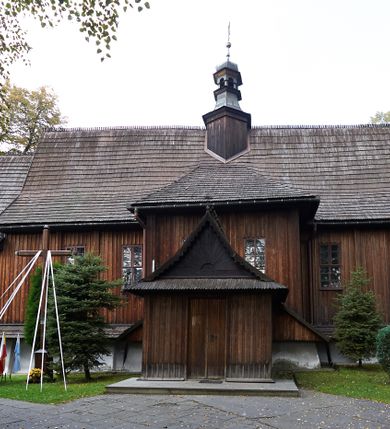 Zdjęcie nr 11: Kościół orientowany, pierwotnie na rzucie krzyża łacińskiego, jednonawowy, z kaplicami bocznymi od północy i południa, z prezbiterium prostokątnym zamkniętym wielobocznie. Obecnie w miejscu drewnianej kaplicy północnej murowana kaplica grobowa, a przy prezbiterium murowana prostokątna zakrystia i skarbczyk (1622 r.); nawa przedłużona ku zachodowi (1878-1879). Przy zachodniej części nawy, od południa, prostokątna drewniana kruchta. Wewnątrz stropy, w kaplicy północnej sklepienie krzyżowe z lunetami, w zakrystii i skarbczyku kolebkowe z lunetami. Zewnątrz zaszalowany. Dach nad nawą i prezbiterium jednokalenicowy, dwuspadowy o załamanych połaciach. Na kalenicy baniasta wieżyczka na sygnaturkę. Odrzwia zachodnie z nadprożem ozdobionym trójliściem z łukiem w ośli grzbiet oraz fryzem arkadkowym; odrzwia z prezbiterium do zakrystii z nadprożem ozdobionym łukiem w ośli grzbiet.