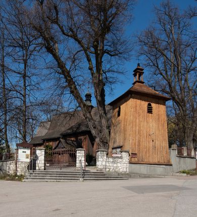 Zdjęcie nr 4: Kościół orientowany, pierwotnie na rzucie krzyża łacińskiego, jednonawowy, z kaplicami bocznymi od północy i południa, z prezbiterium prostokątnym zamkniętym wielobocznie. Obecnie w miejscu drewnianej kaplicy północnej murowana kaplica grobowa, a przy prezbiterium murowana prostokątna zakrystia i skarbczyk (1622 r.); nawa przedłużona ku zachodowi (1878-1879). Przy zachodniej części nawy, od południa, prostokątna drewniana kruchta. Wewnątrz stropy, w kaplicy północnej sklepienie krzyżowe z lunetami, w zakrystii i skarbczyku kolebkowe z lunetami. Zewnątrz zaszalowany. Dach nad nawą i prezbiterium jednokalenicowy, dwuspadowy o załamanych połaciach. Na kalenicy baniasta wieżyczka na sygnaturkę. Odrzwia zachodnie z nadprożem ozdobionym trójliściem z łukiem w ośli grzbiet oraz fryzem arkadkowym; odrzwia z prezbiterium do zakrystii z nadprożem ozdobionym łukiem w ośli grzbiet.