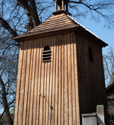 Zdjęcie nr 7: Kościół orientowany, pierwotnie na rzucie krzyża łacińskiego, jednonawowy, z kaplicami bocznymi od północy i południa, z prezbiterium prostokątnym zamkniętym wielobocznie. Obecnie w miejscu drewnianej kaplicy północnej murowana kaplica grobowa, a przy prezbiterium murowana prostokątna zakrystia i skarbczyk (1622 r.); nawa przedłużona ku zachodowi (1878-1879). Przy zachodniej części nawy, od południa, prostokątna drewniana kruchta. Wewnątrz stropy, w kaplicy północnej sklepienie krzyżowe z lunetami, w zakrystii i skarbczyku kolebkowe z lunetami. Zewnątrz zaszalowany. Dach nad nawą i prezbiterium jednokalenicowy, dwuspadowy o załamanych połaciach. Na kalenicy baniasta wieżyczka na sygnaturkę. Odrzwia zachodnie z nadprożem ozdobionym trójliściem z łukiem w ośli grzbiet oraz fryzem arkadkowym; odrzwia z prezbiterium do zakrystii z nadprożem ozdobionym łukiem w ośli grzbiet.